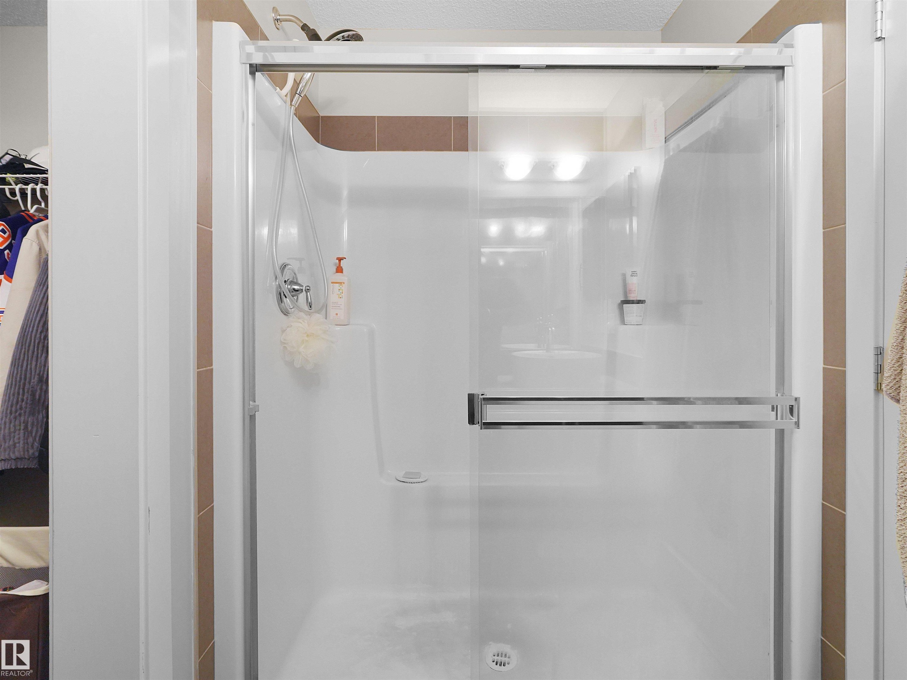 Shower enclosure with clear glass sliding door, chrome hardware, and tiled surround - #89 603 Watt Bv Sw, Edmonton, AB - Indoor Photo Showing Bathroom