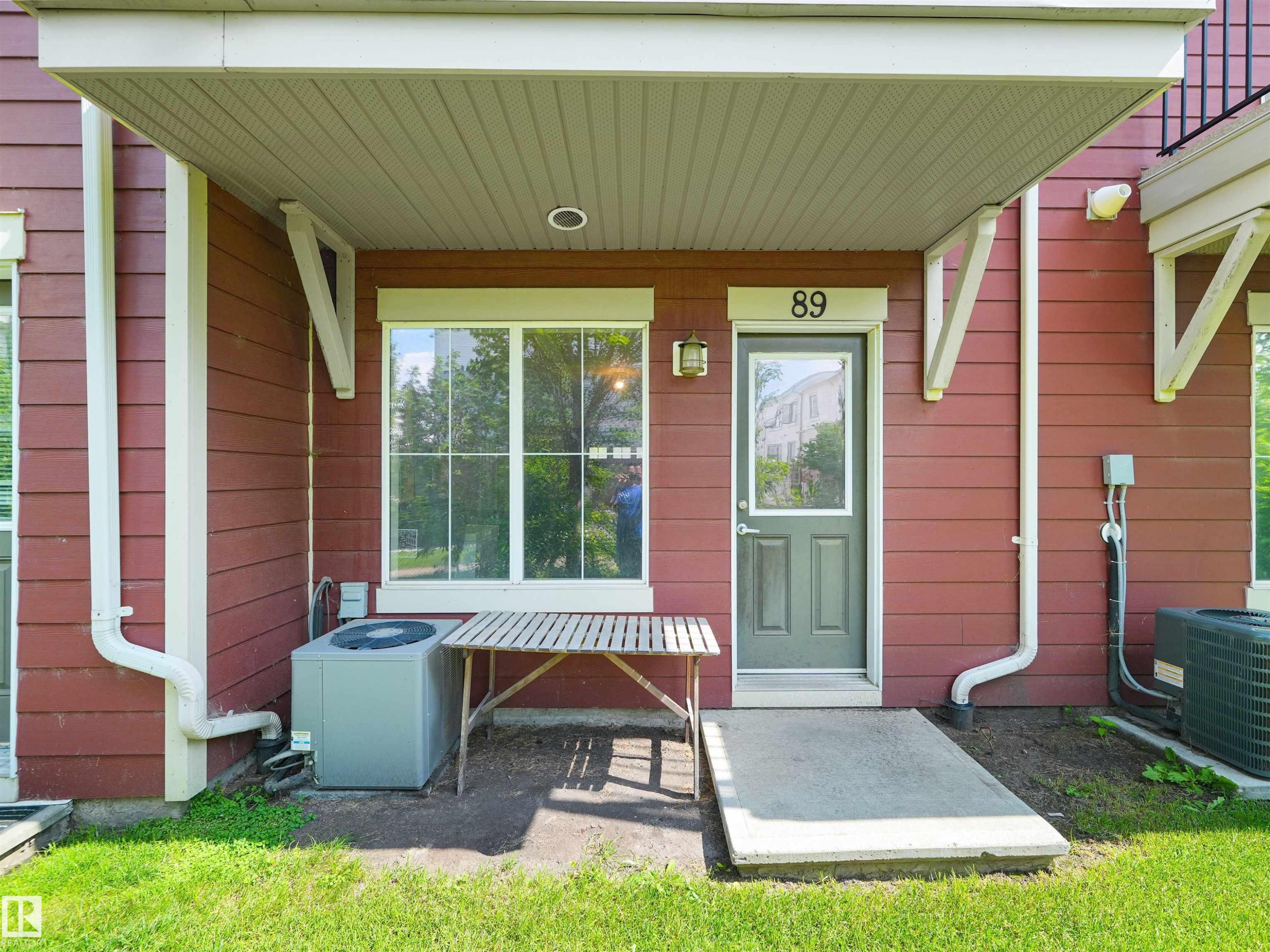 Red horizontal siding with white trim, covered patio, and a concrete pathway - #89 603 Watt Bv Sw, Edmonton, AB - Outdoor With Exterior