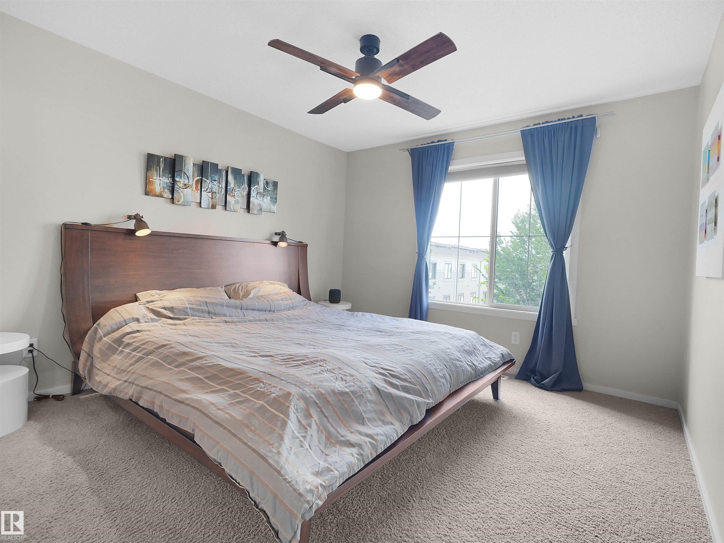 Carpeted room featuring a ceiling fan, a large window, and light-toned walls - #89 603 Watt Bv Sw, Edmonton, AB - Indoor Photo Showing Bedroom