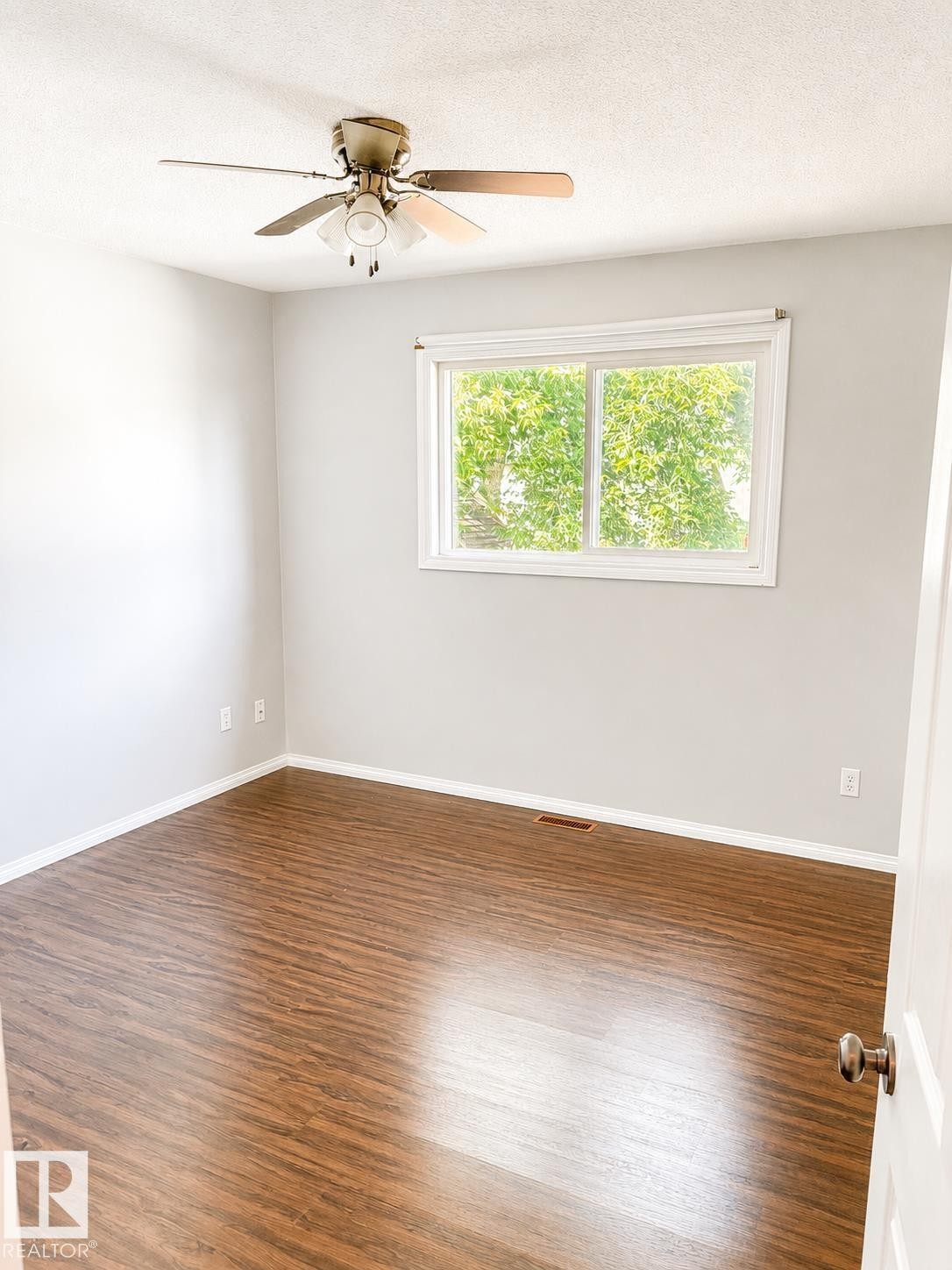 Wood-finish flooring, white trim, recessed window with white framing, and a ceiling fan with integrated lighting - 802 16 Avenue, Cold Lake, AB - Indoor Photo Showing Other Room