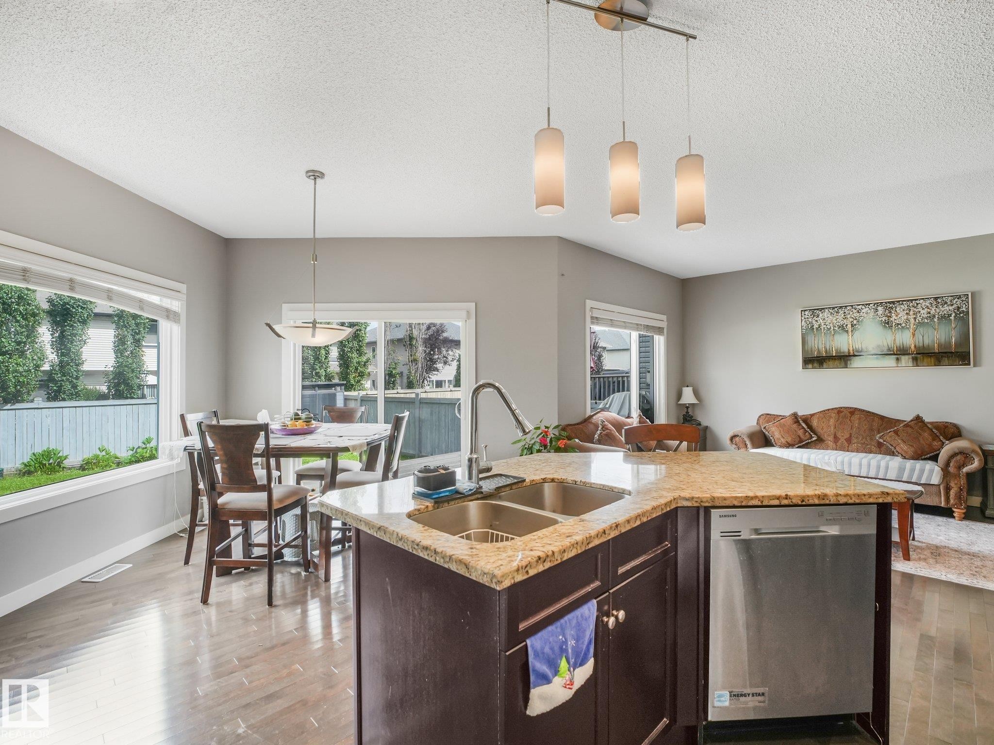 Kitchen island with dual stainless steel sinks, granite-style countertop, and integrated dishwasher - 1478 37B Avenue Nw, Edmonton, AB - Indoor