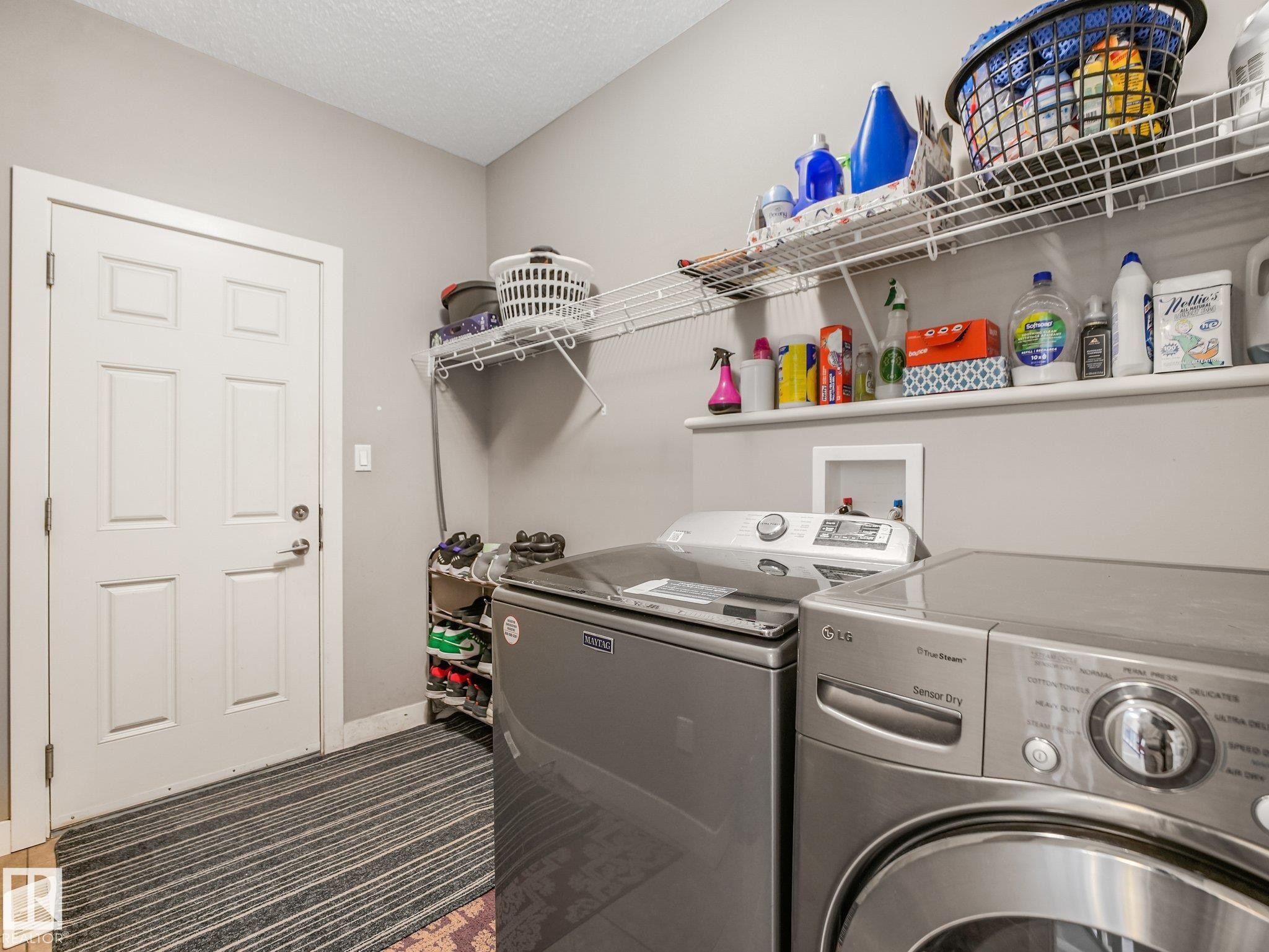 Dedicated laundry space featuring a white paneled door, light-toned walls, and built-in wire shelving - 1478 37B Avenue Nw, Edmonton, AB - Indoor Photo Showing Laundry Room
