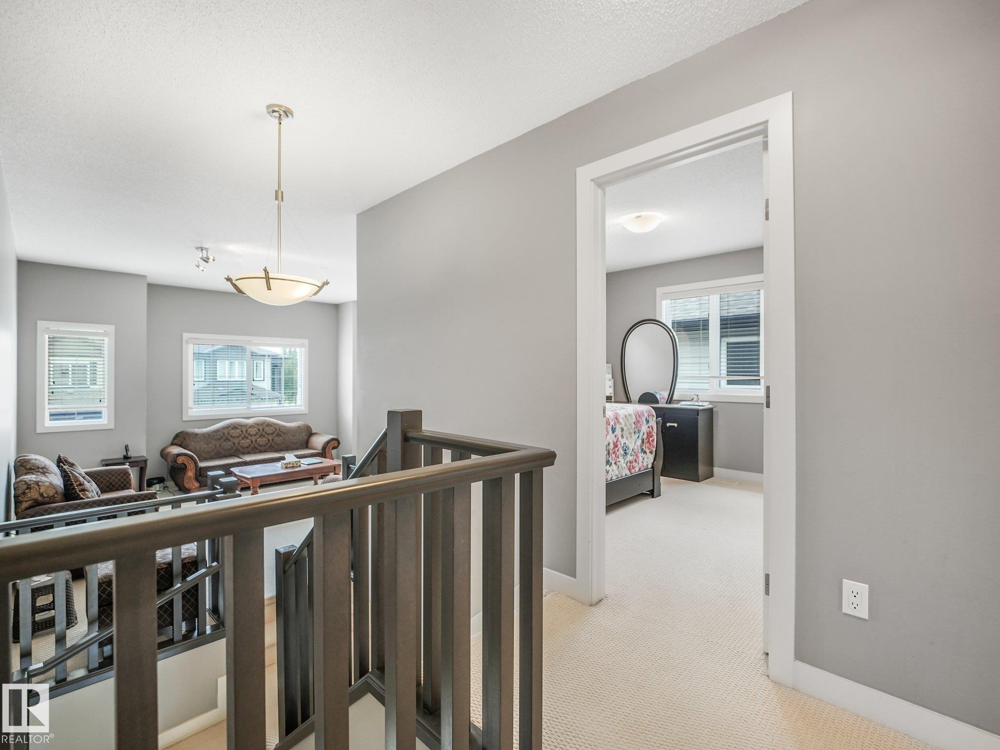 Upper-level landing with carpeted flooring and a built-in wood-finish railing - 1478 37B Avenue Nw, Edmonton, AB - Indoor