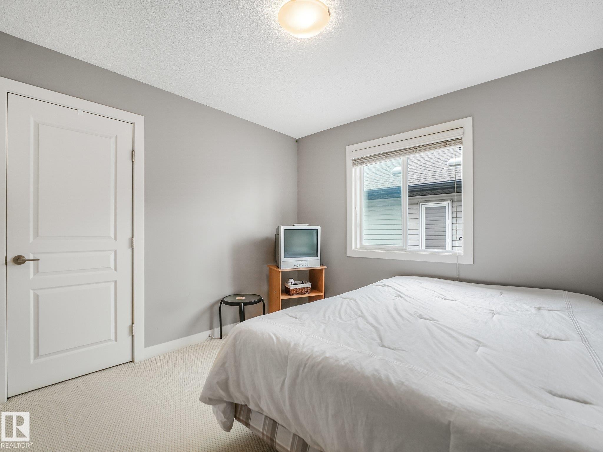 Neutral gray walls, white painted trim, white panel door, carpeted flooring, and a single window - 1478 37B Avenue Nw, Edmonton, AB - Indoor Photo Showing Bedroom