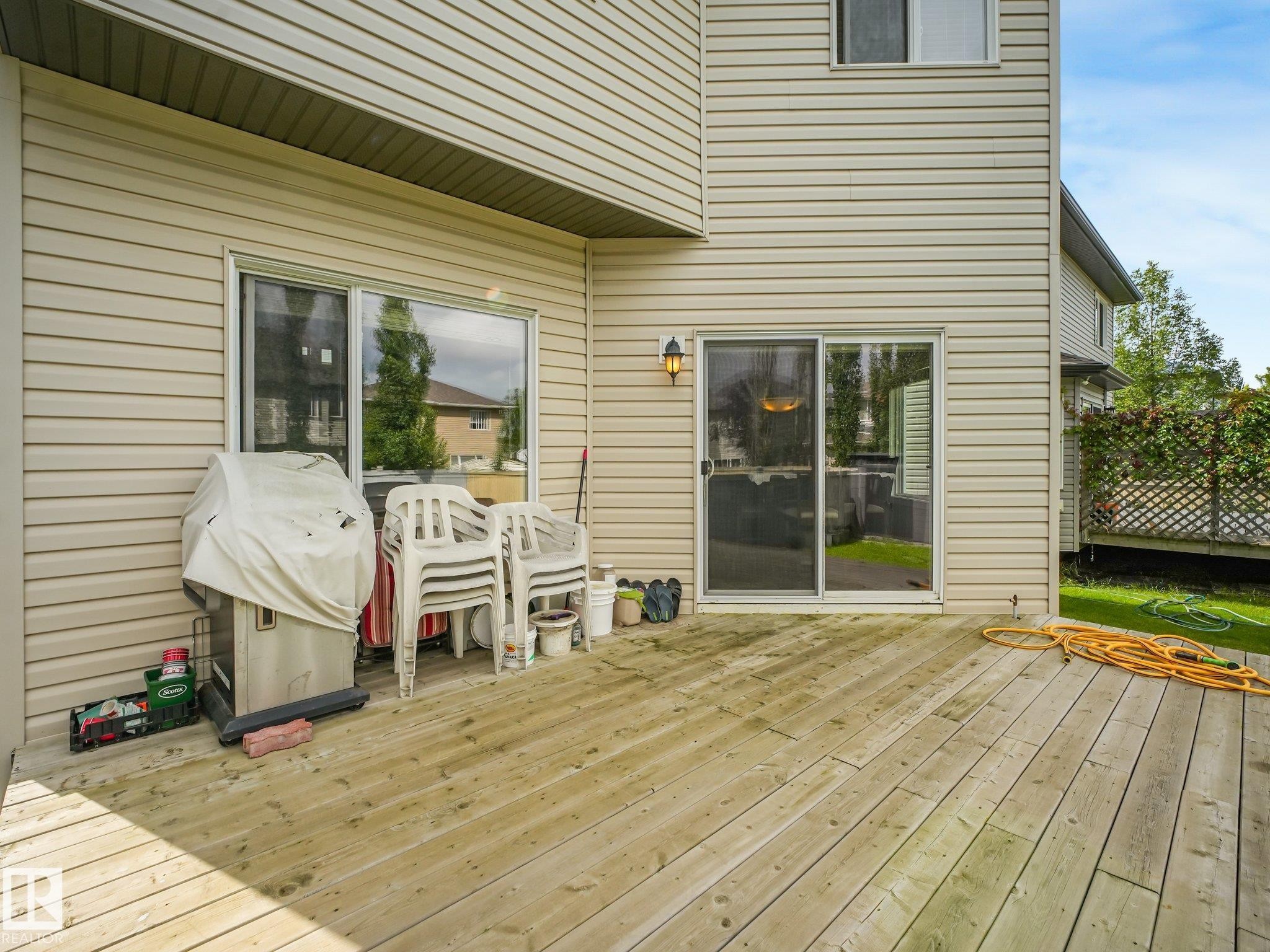 Expansive wood deck with a sliding glass door and an exterior light fixture - 1478 37B Avenue Nw, Edmonton, AB - Outdoor With Deck Patio Veranda With Exterior