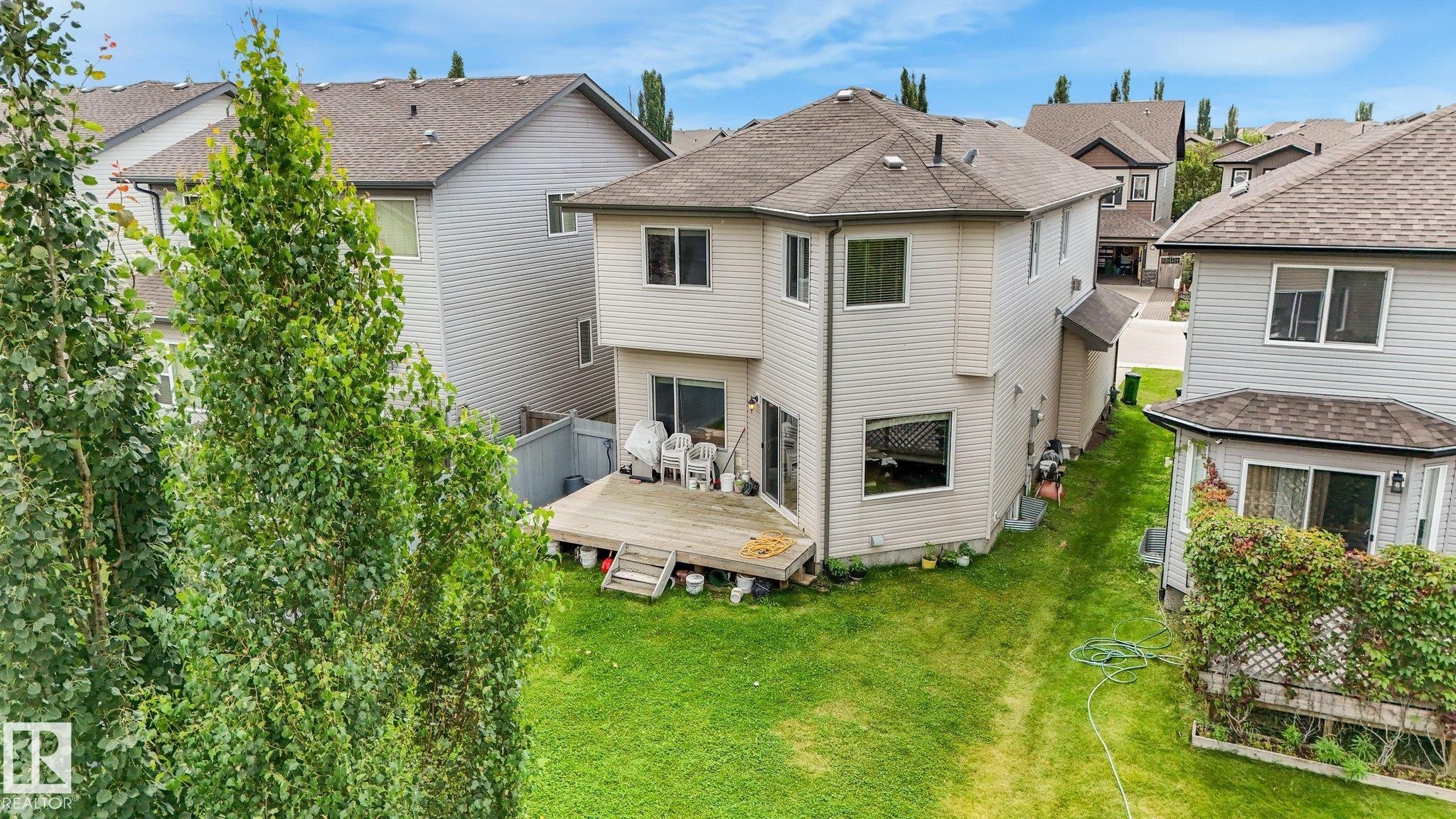 Expansive backyard featuring a manicured lawn, a large wood deck, and mature perimeter trees - 1478 37B Avenue Nw, Edmonton, AB - Outdoor