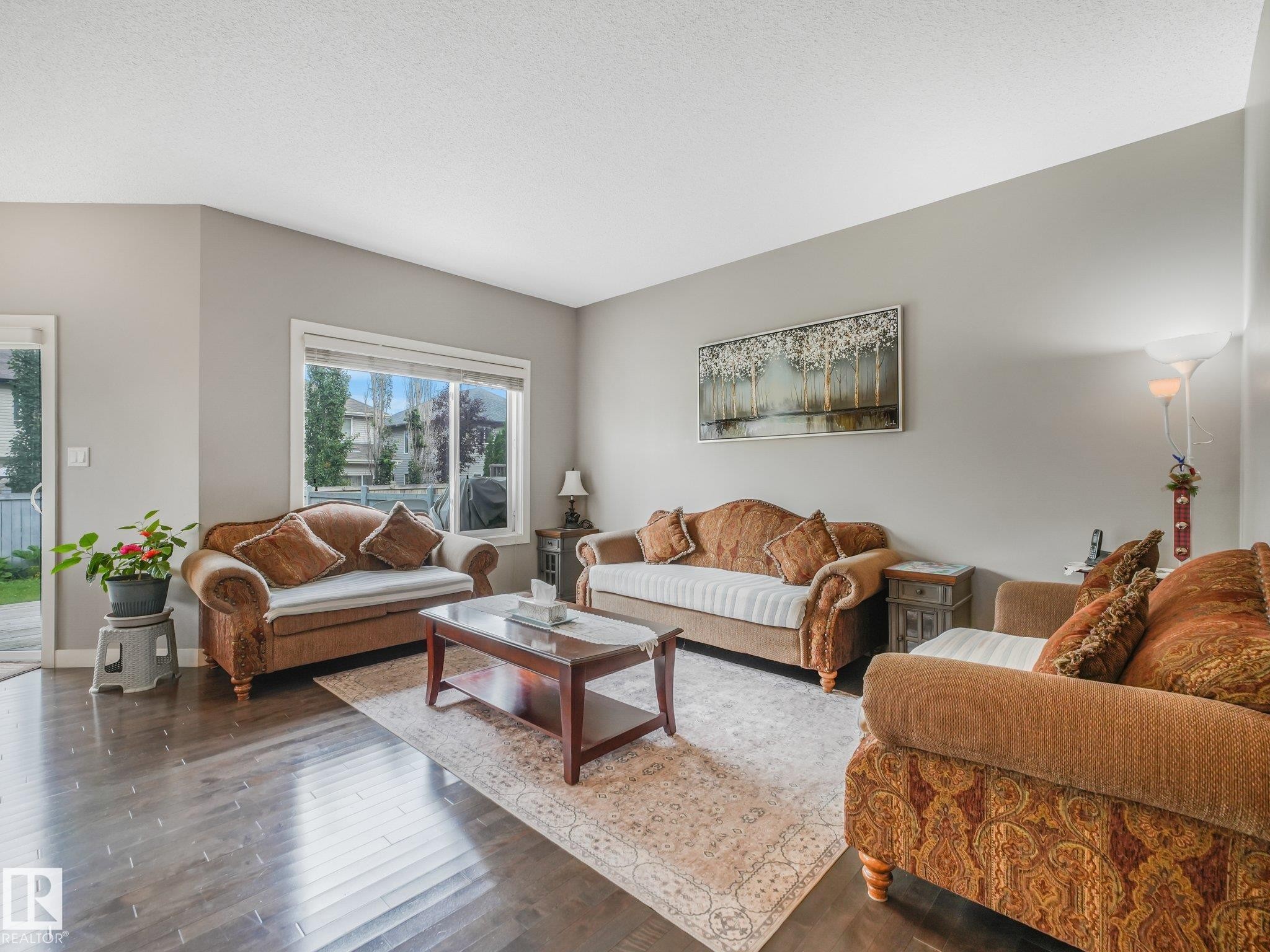 Wood-finish flooring, neutral wall tones, and expansive windows - 1478 37B Avenue Nw, Edmonton, AB - Indoor Photo Showing Living Room