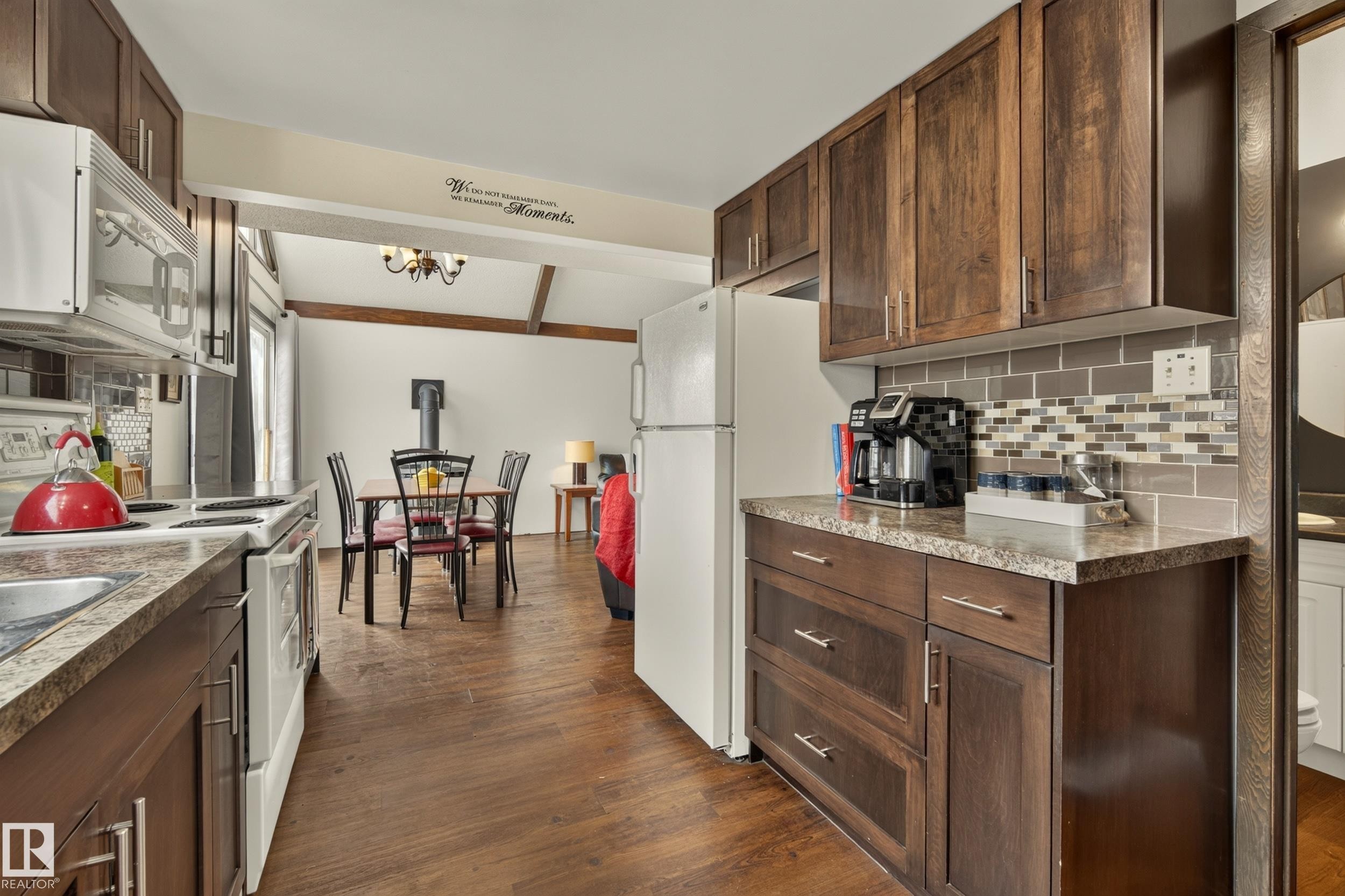 Kitchen featuring wood-finish cabinetry, stone-look countertops, and a subway tile backsplash - 264 Beach Avenue, Rural Barrhead County, AB - Indoor Photo Showing Kitchen