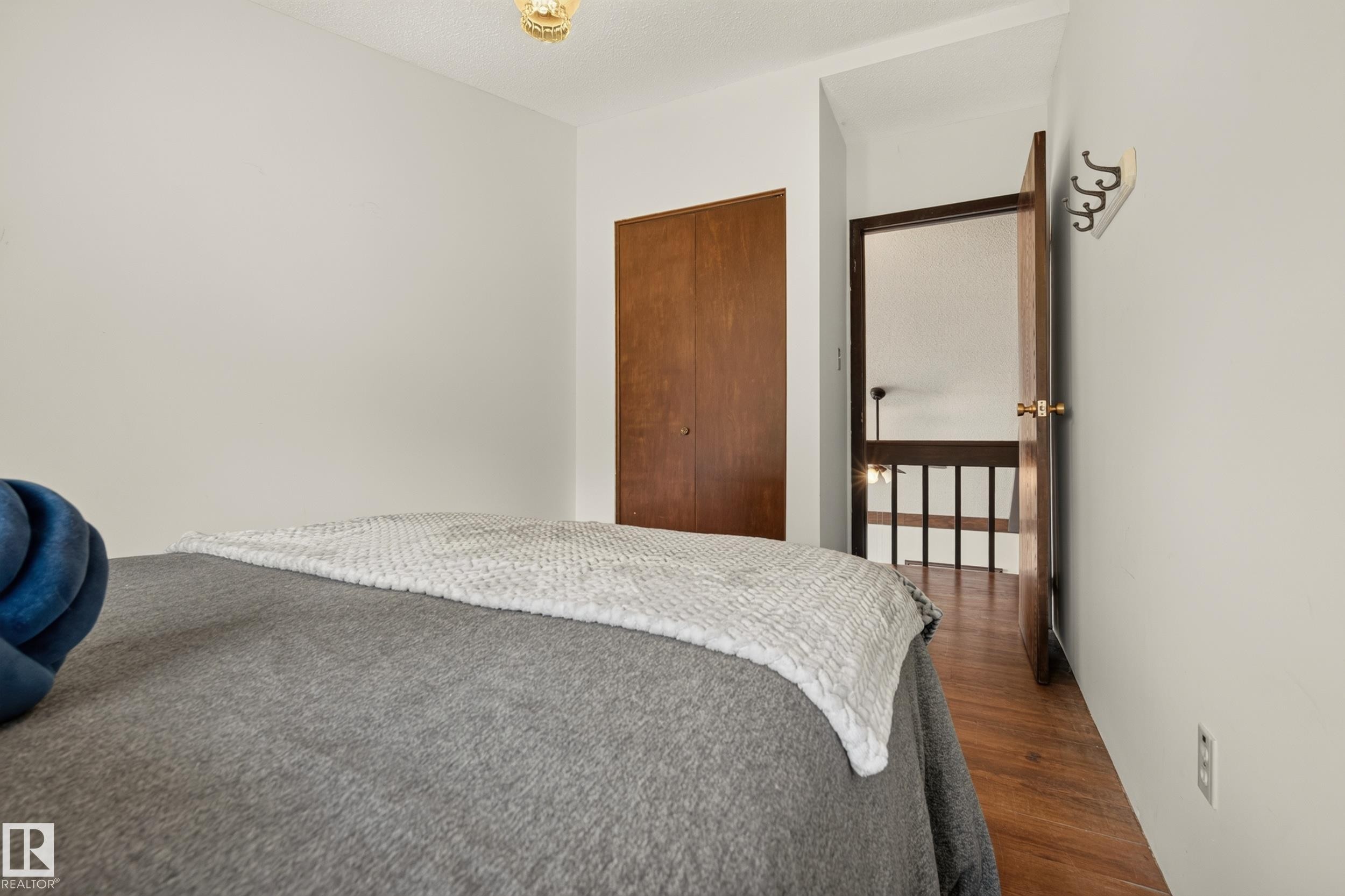Wood-finish flooring, wood bi-fold closet doors, and a wood-paneled door - 264 Beach Avenue, Rural Barrhead County, AB - Indoor Photo Showing Bedroom