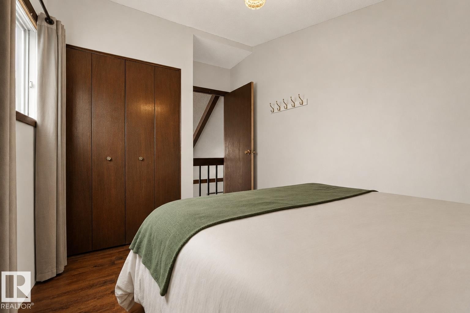 Wood-finish flooring with a multi-panel closet, a single window, and a built-in wall rack - 264 Beach Avenue, Rural Barrhead County, AB - Indoor Photo Showing Bedroom