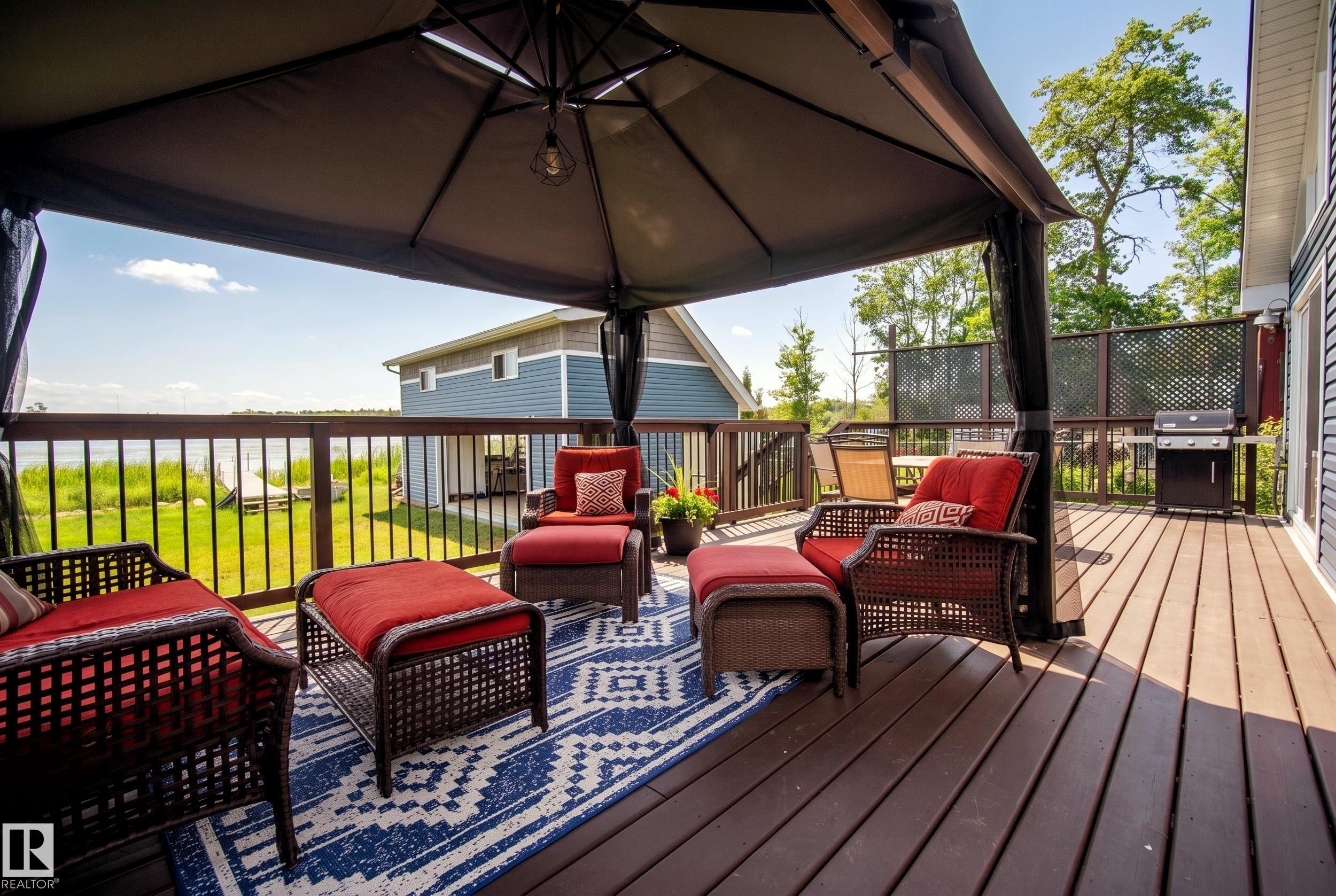 Expansive outdoor deck featuring wood-finish flooring, a gazebo, and a dark metal railing - 264 Beach Avenue, Rural Barrhead County, AB - Outdoor With Deck Patio Veranda With Exterior