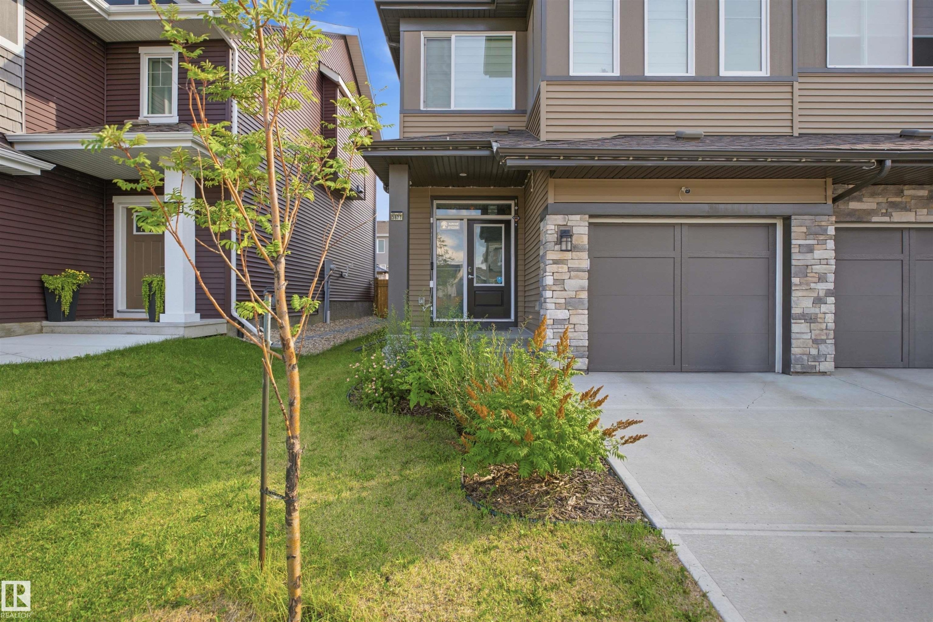 Contemporary exterior with stone accents, concrete driveway, and attached garage - 3877 Chrustawka Place Sw, Edmonton, AB - Outdoor With Facade