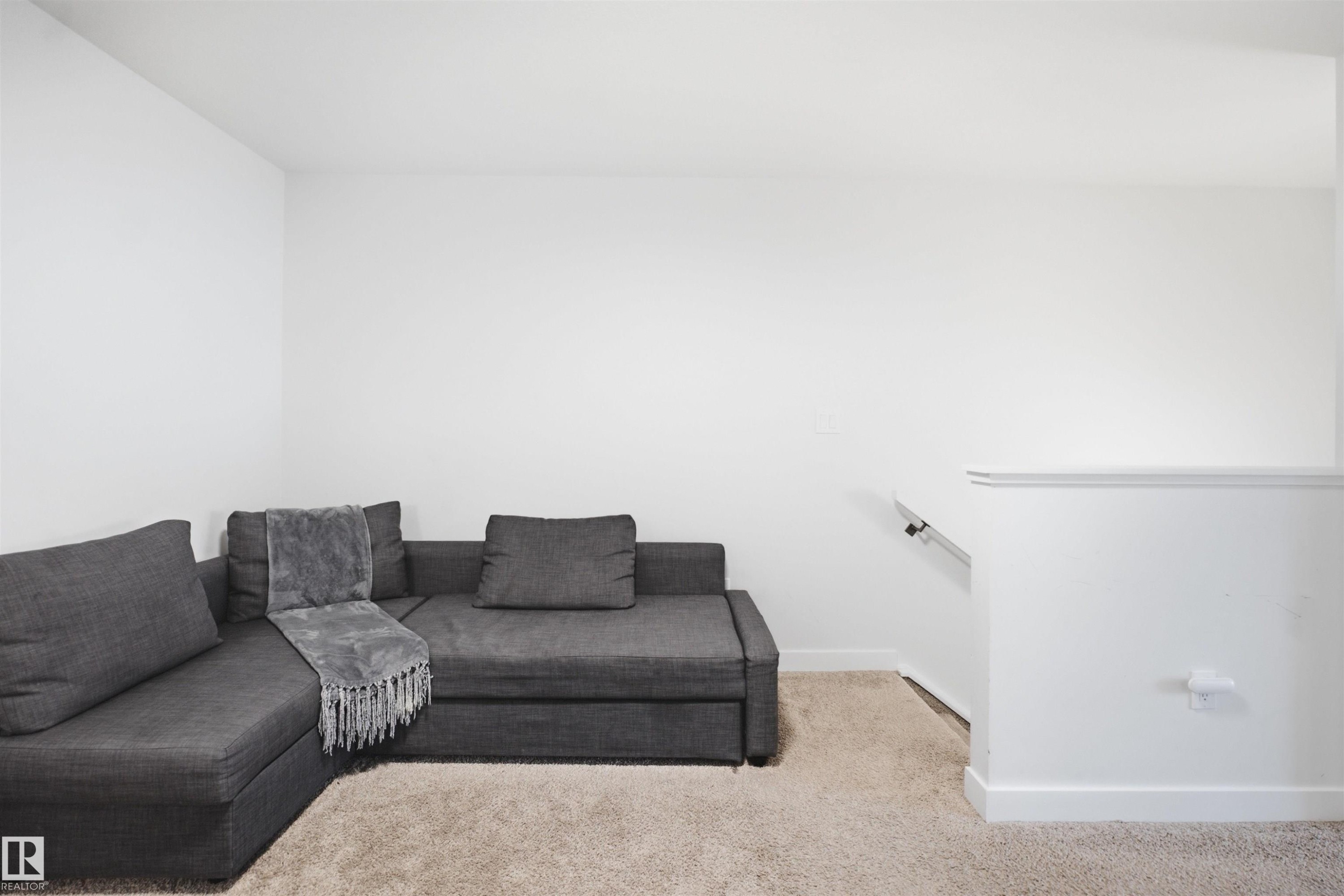 Plush carpet flooring, neutral wall tones, and a white handrail - 3877 Chrustawka Place Sw, Edmonton, AB - Indoor Photo Showing Living Room