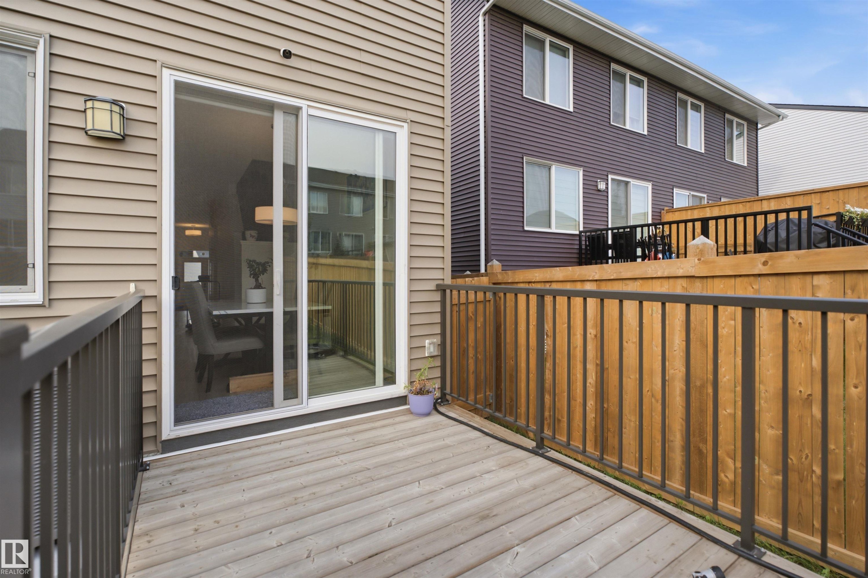 Private deck with wood decking, black metal railing, and a sliding glass door - 3877 Chrustawka Place Sw, Edmonton, AB - Outdoor With Deck Patio Veranda With Exterior