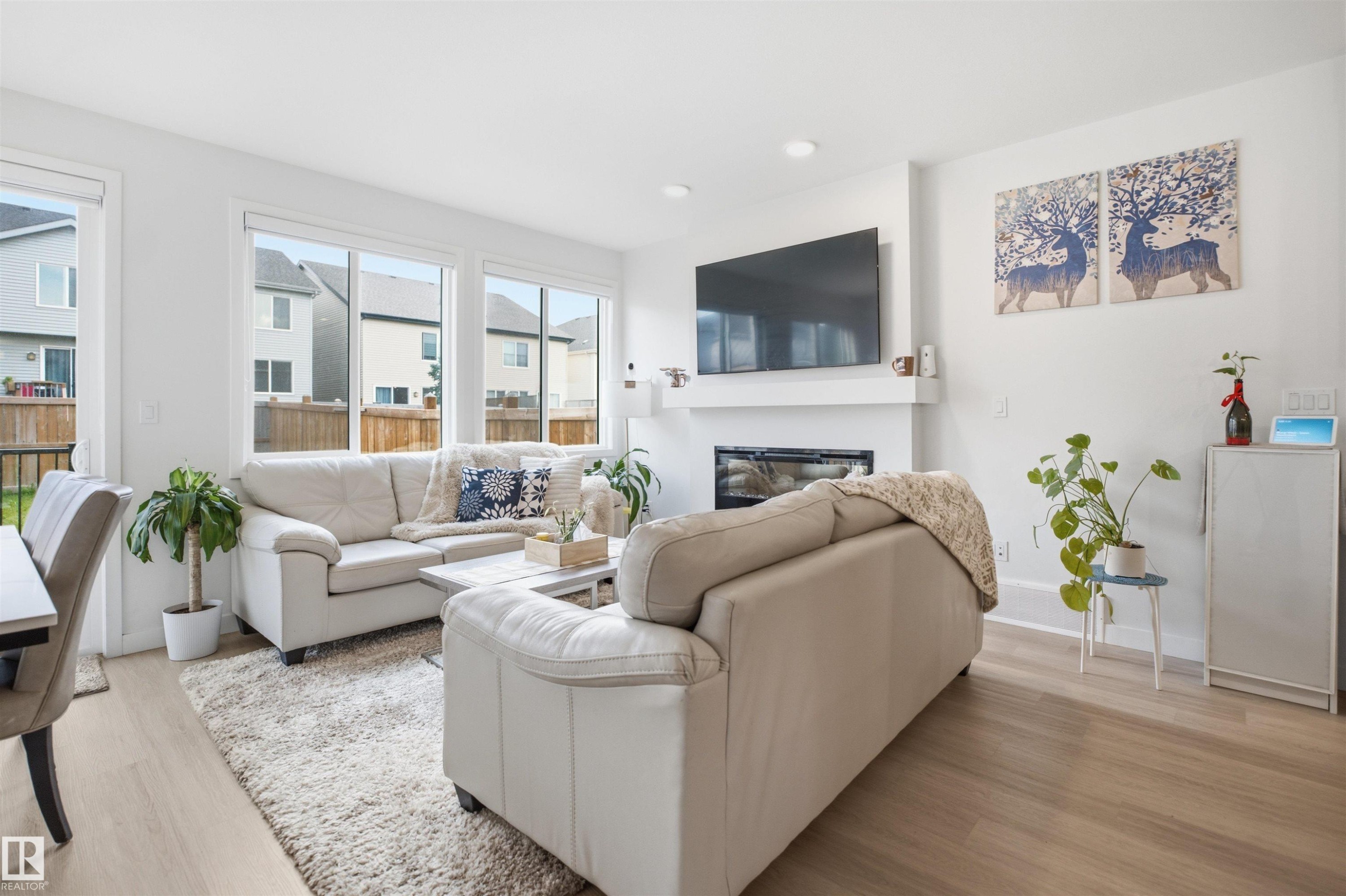 Living area featuring light wood-finish flooring, recessed lighting, and a contemporary fireplace with a white mantel - 3877 Chrustawka Place Sw, Edmonton, AB - Indoor Photo Showing Living Room With Fireplace