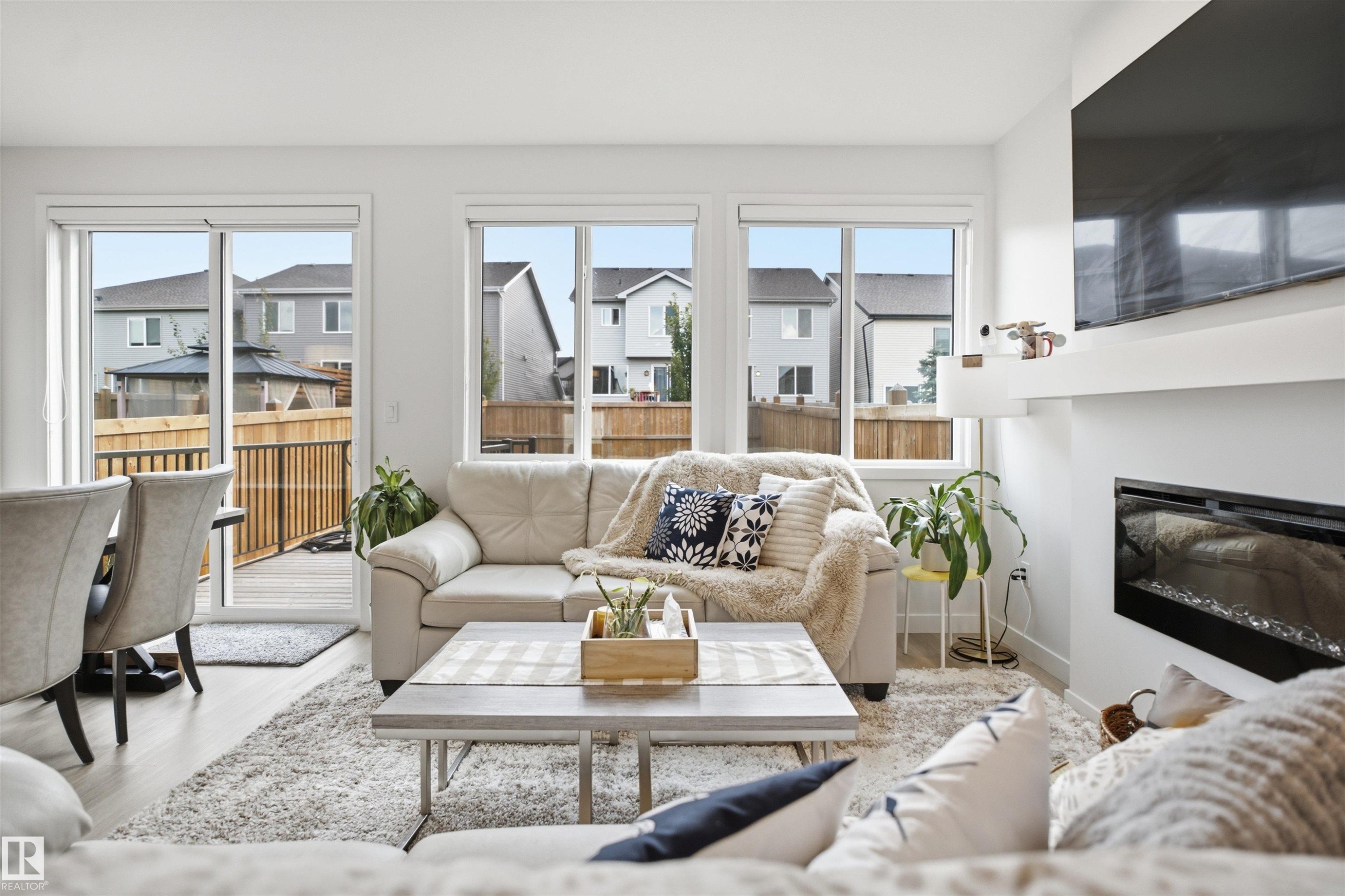 Living area featuring a built-in electric fireplace, white mantel, and wood-finish flooring - 3877 Chrustawka Place Sw, Edmonton, AB - Indoor Photo Showing Living Room With Fireplace