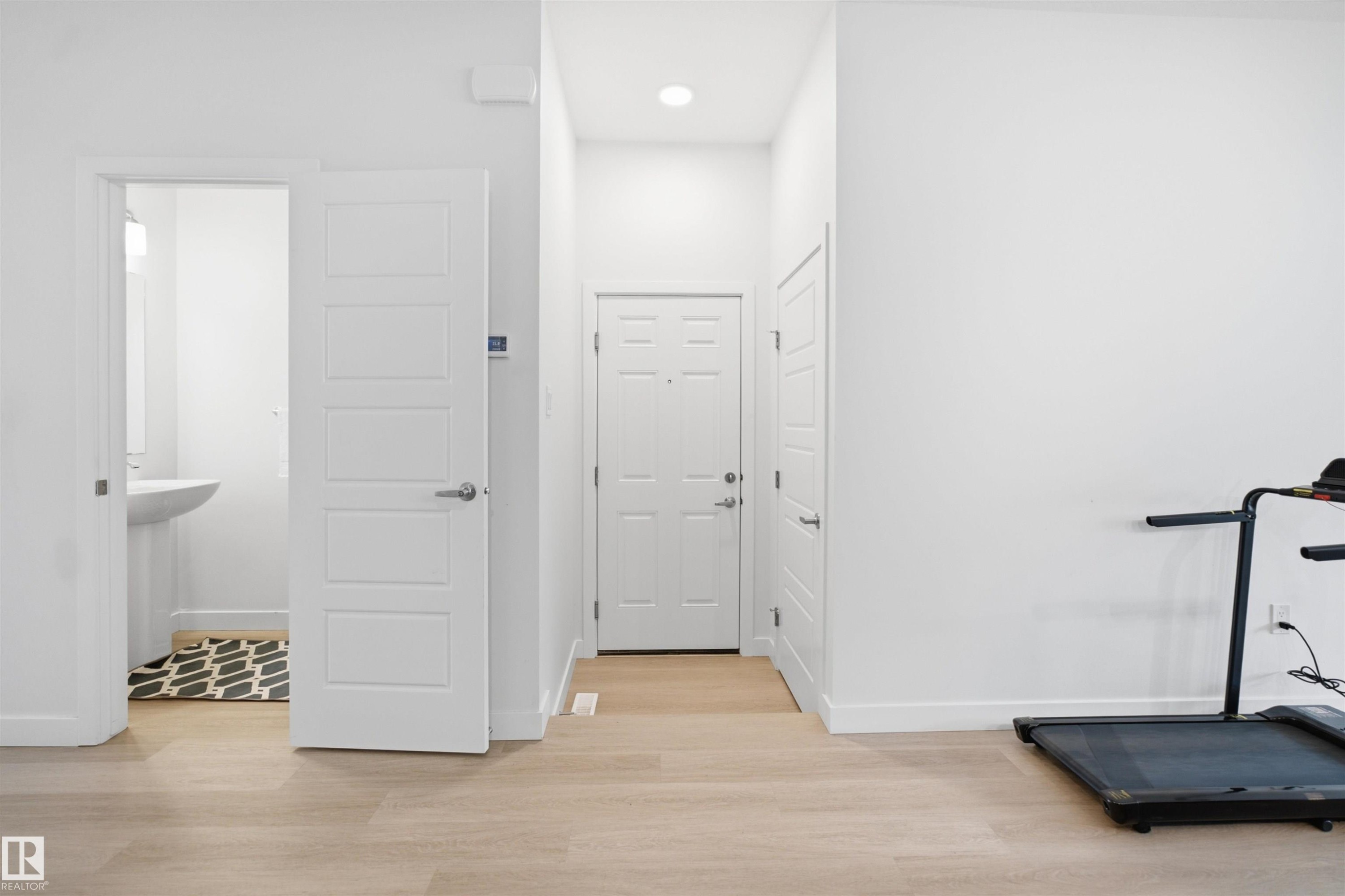Light wood-finish flooring throughout, white interior doors with contemporary hardware, and recessed ceiling lighting - 3877 Chrustawka Place Sw, Edmonton, AB - Indoor