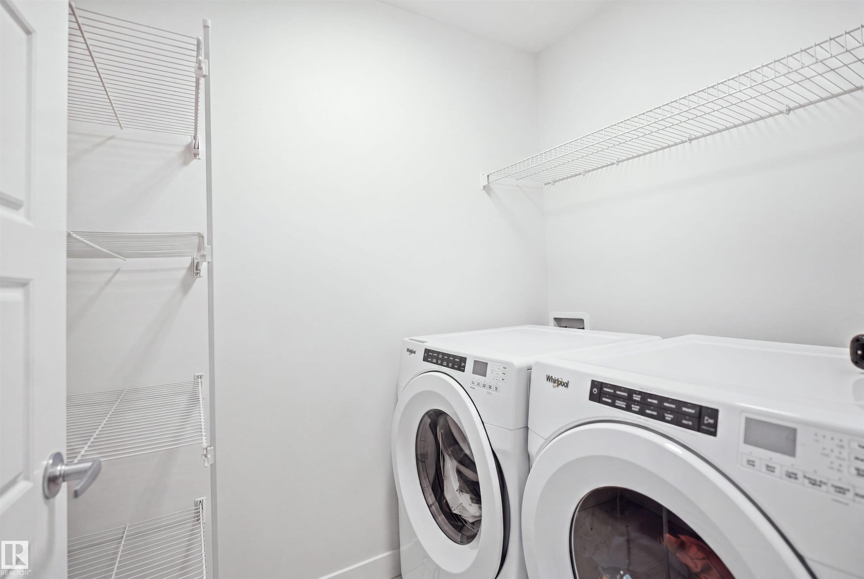 Laundry area with a side-by-side washer and dryer, wire shelving, and a white paneled door - 3877 Chrustawka Place Sw, Edmonton, AB - Indoor Photo Showing Laundry Room