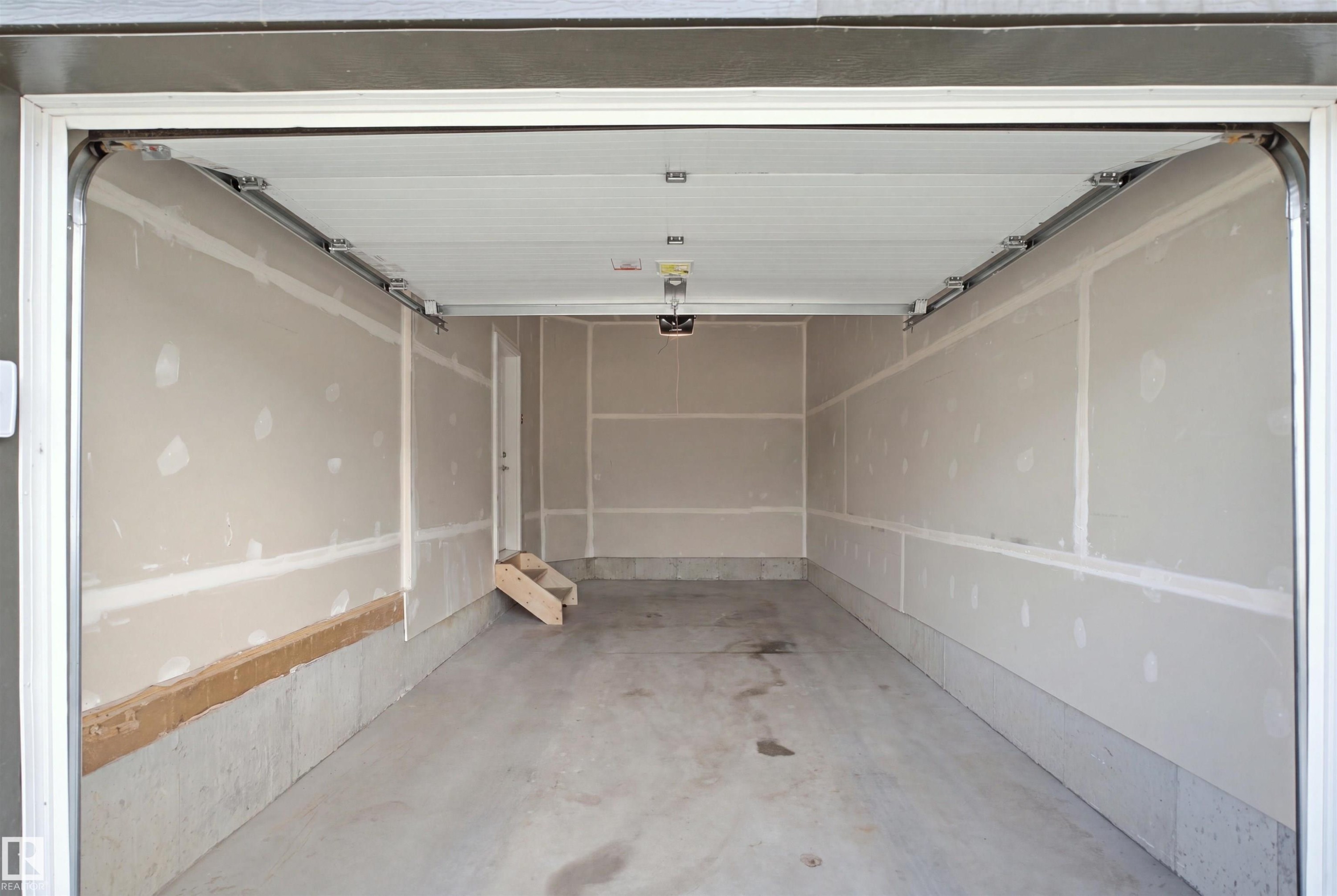 Unfinished garage interior featuring a concrete floor, concrete foundation, and partially finished drywall walls - 3877 Chrustawka Place Sw, Edmonton, AB - Indoor