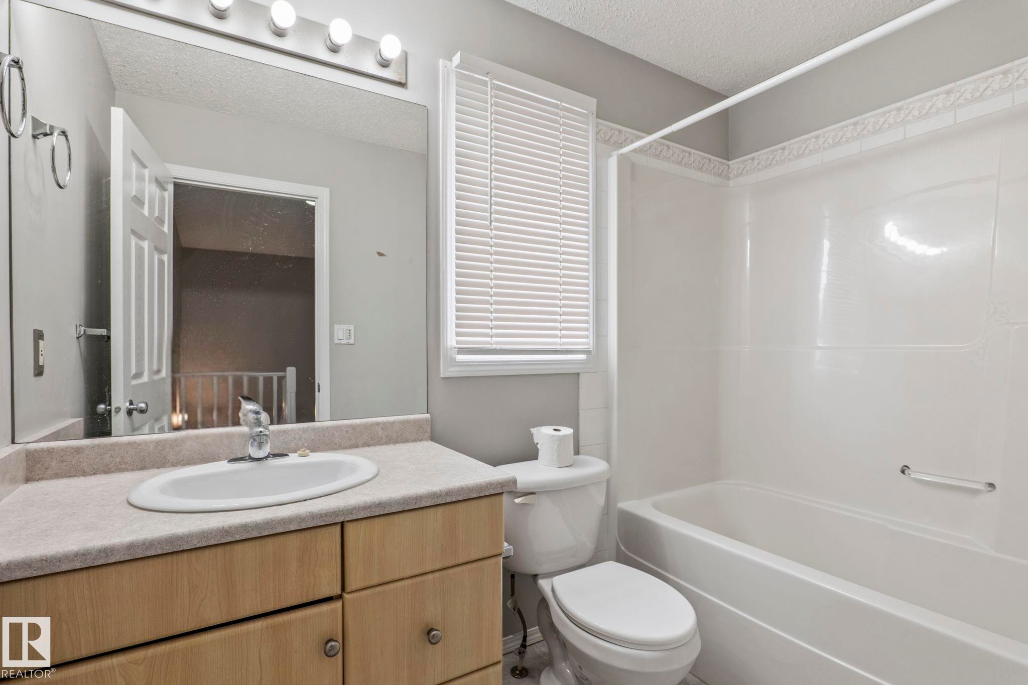 Vanity with wood-finish cabinetry and integrated sink - #80 4350 23St Nw, Edmonton, AB - Indoor Photo Showing Bathroom