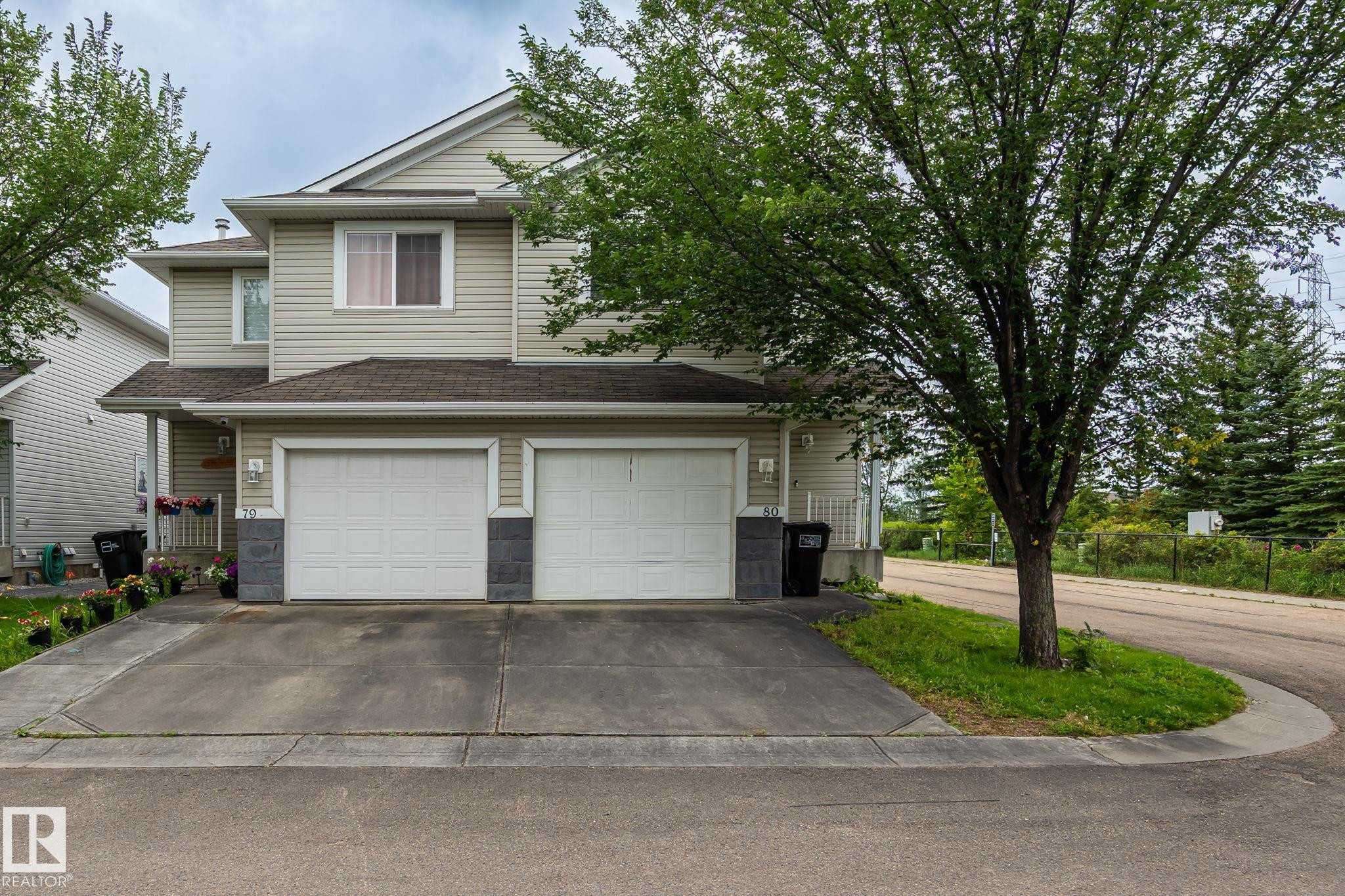 Two-story residence with siding exterior, dual garage doors, and a concrete driveway - #80 4350 23St Nw, Edmonton, AB - Outdoor With Facade
