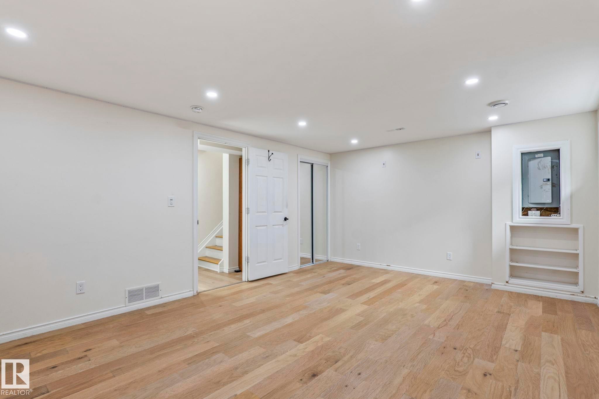 Recessed ceiling lighting, wood-finish flooring, built-in shelving, white paneled doors, and mirrored sliding closet doors - #80 4350 23St Nw, Edmonton, AB - Indoor