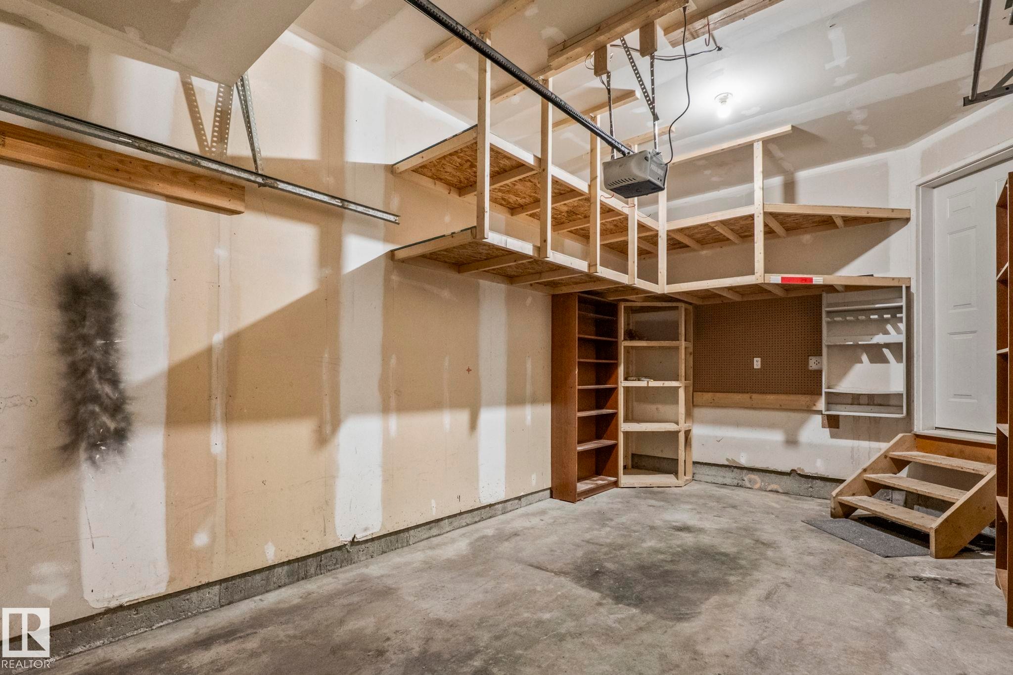 Garage featuring concrete flooring, built-in wooden shelving, and an overhead storage system - #80 4350 23St Nw, Edmonton, AB - Indoor Photo Showing Garage