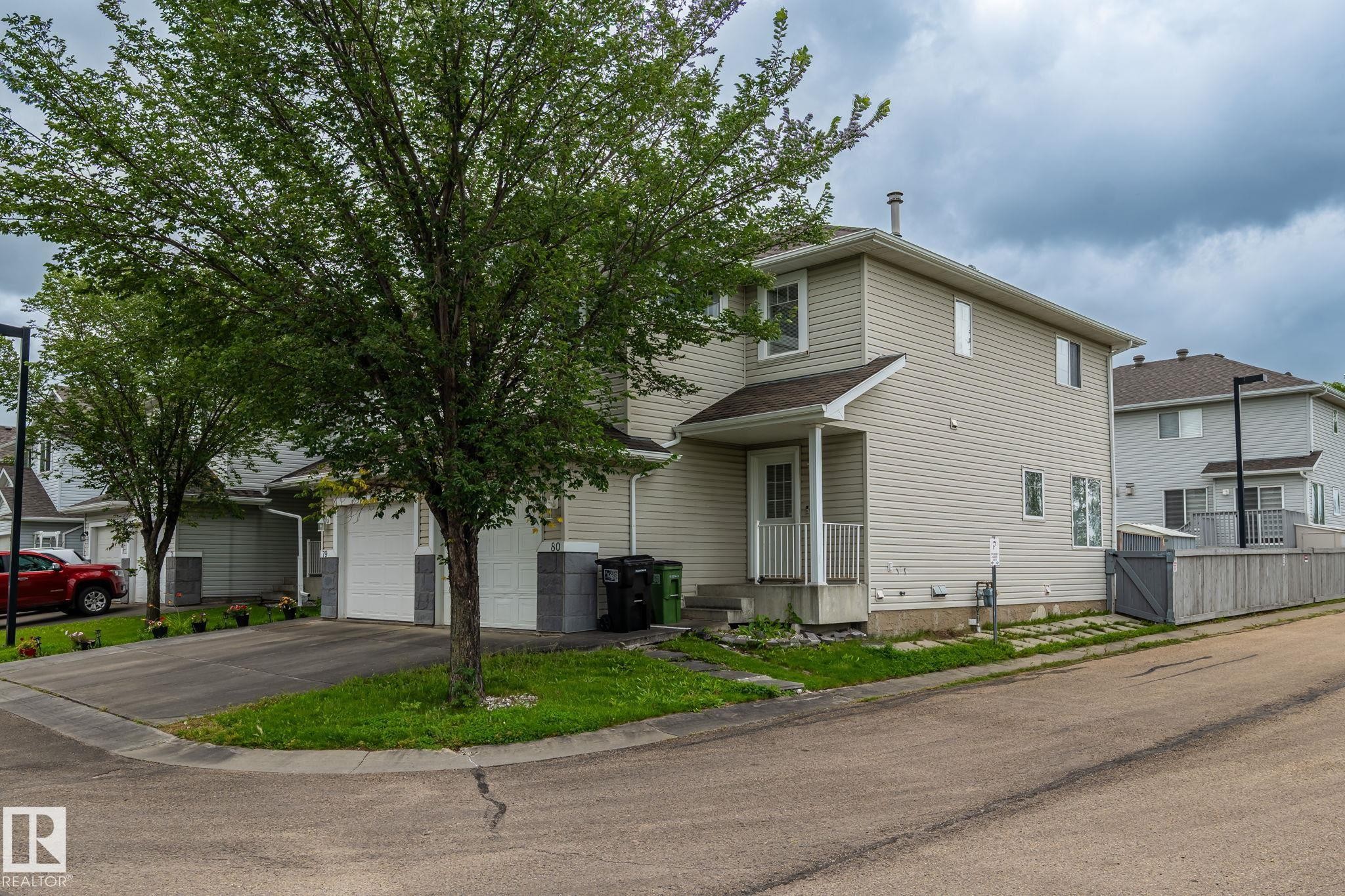 Two-story residence with light-toned siding, a front entry porch, and a fenced backyard - #80 4350 23St Nw, Edmonton, AB - Outdoor