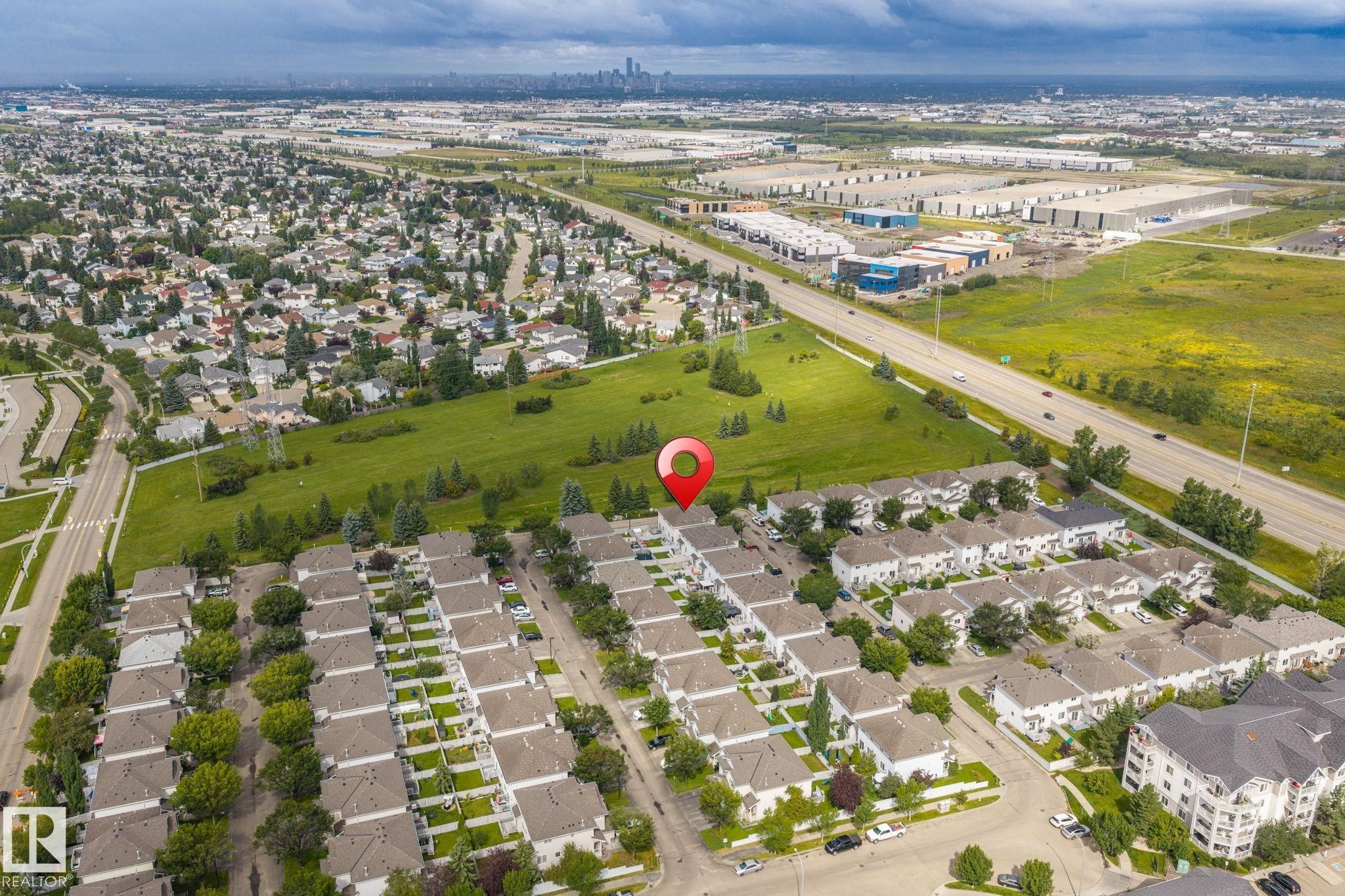 Residential neighborhood featuring rows of detached homes, green spaces, and a major roadway - #80 4350 23St Nw, Edmonton, AB - Outdoor With View