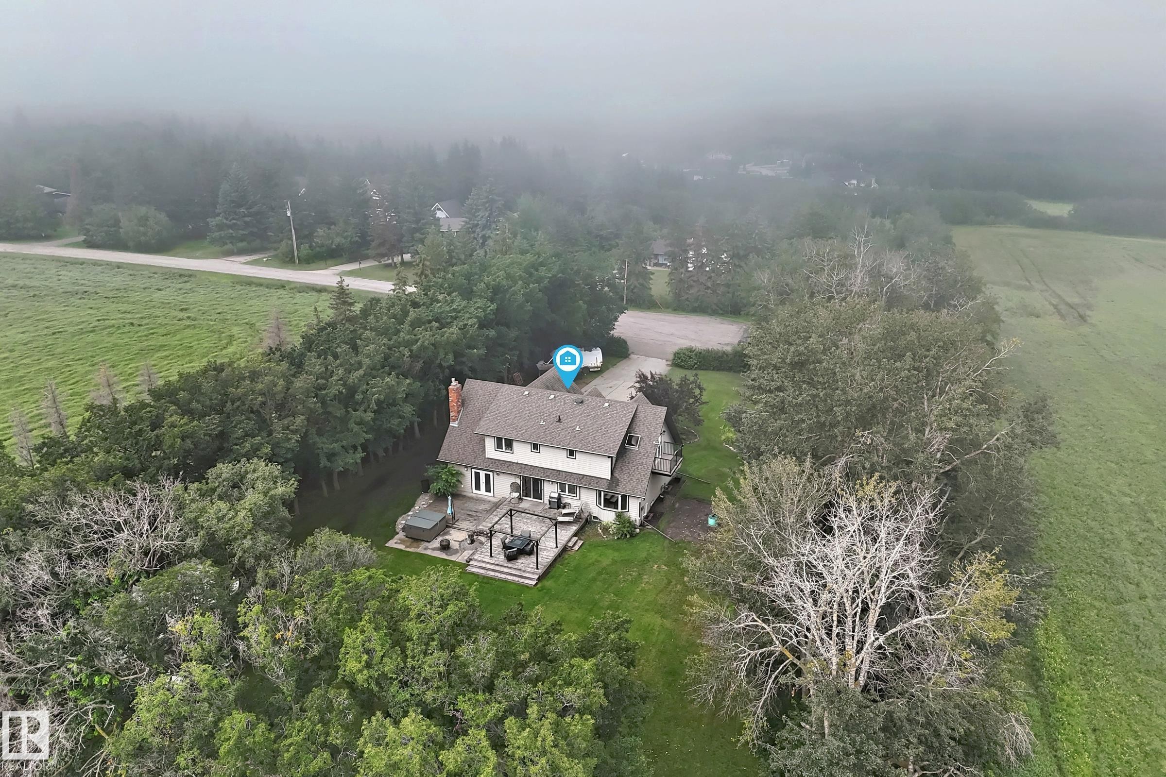 Two-story residence featuring a shingled roof, a chimney, and a rear deck with a pergola - #38 24512 Sturgeon Rd, Rural Sturgeon County, AB