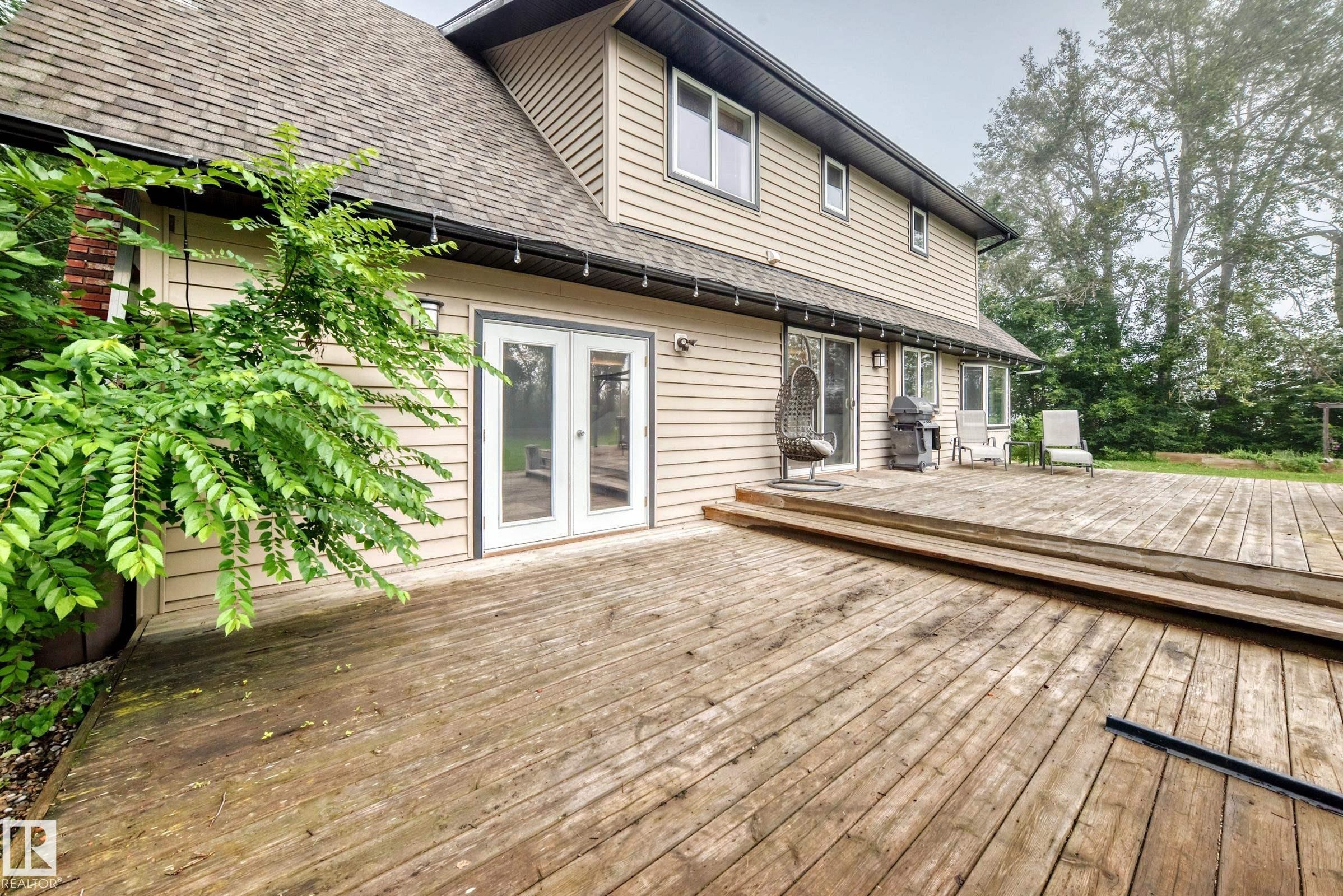 Expansive wood deck with tiered design, multiple access points, and light-toned siding - #38 24512 Sturgeon Rd, Rural Sturgeon County, AB