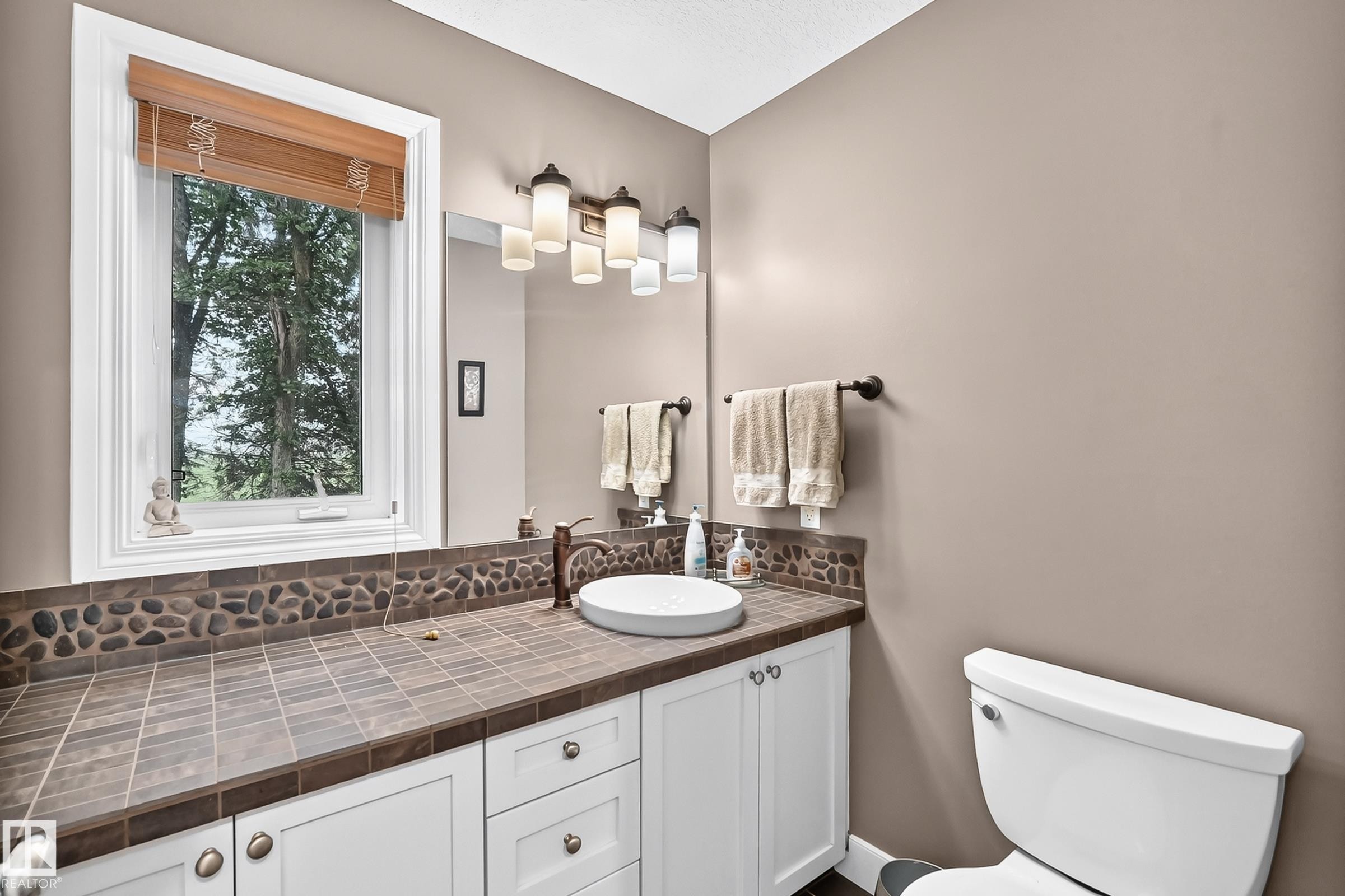 White vanity with shaker-style cabinetry, a white vessel sink, and a bronze-finish faucet - #38 24512 Sturgeon Rd, Rural Sturgeon County, AB