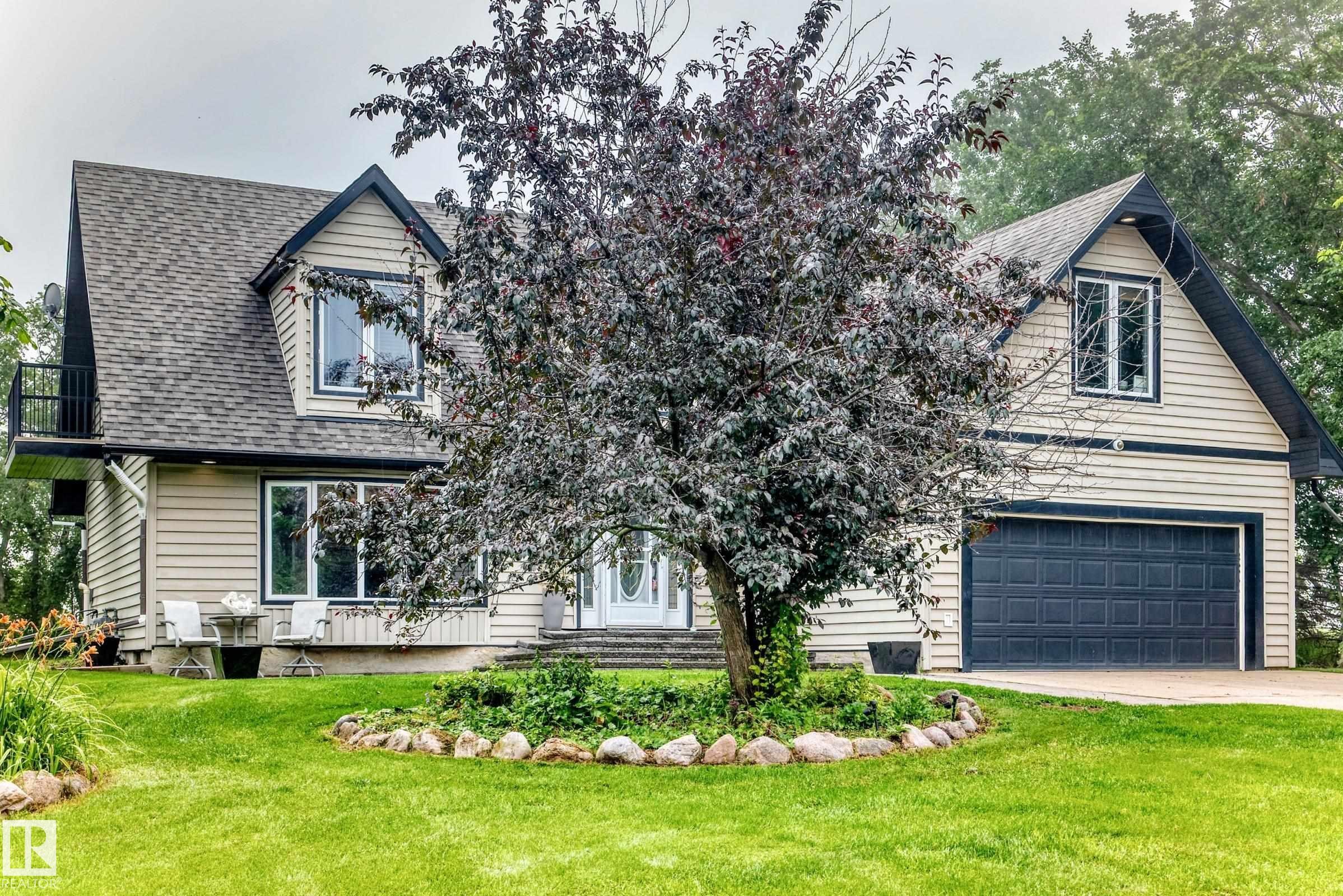 Siding exterior with dormer windows, attached garage, front yard landscaping, and a second-story balcony - #38 24512 Sturgeon Rd, Rural Sturgeon County, AB