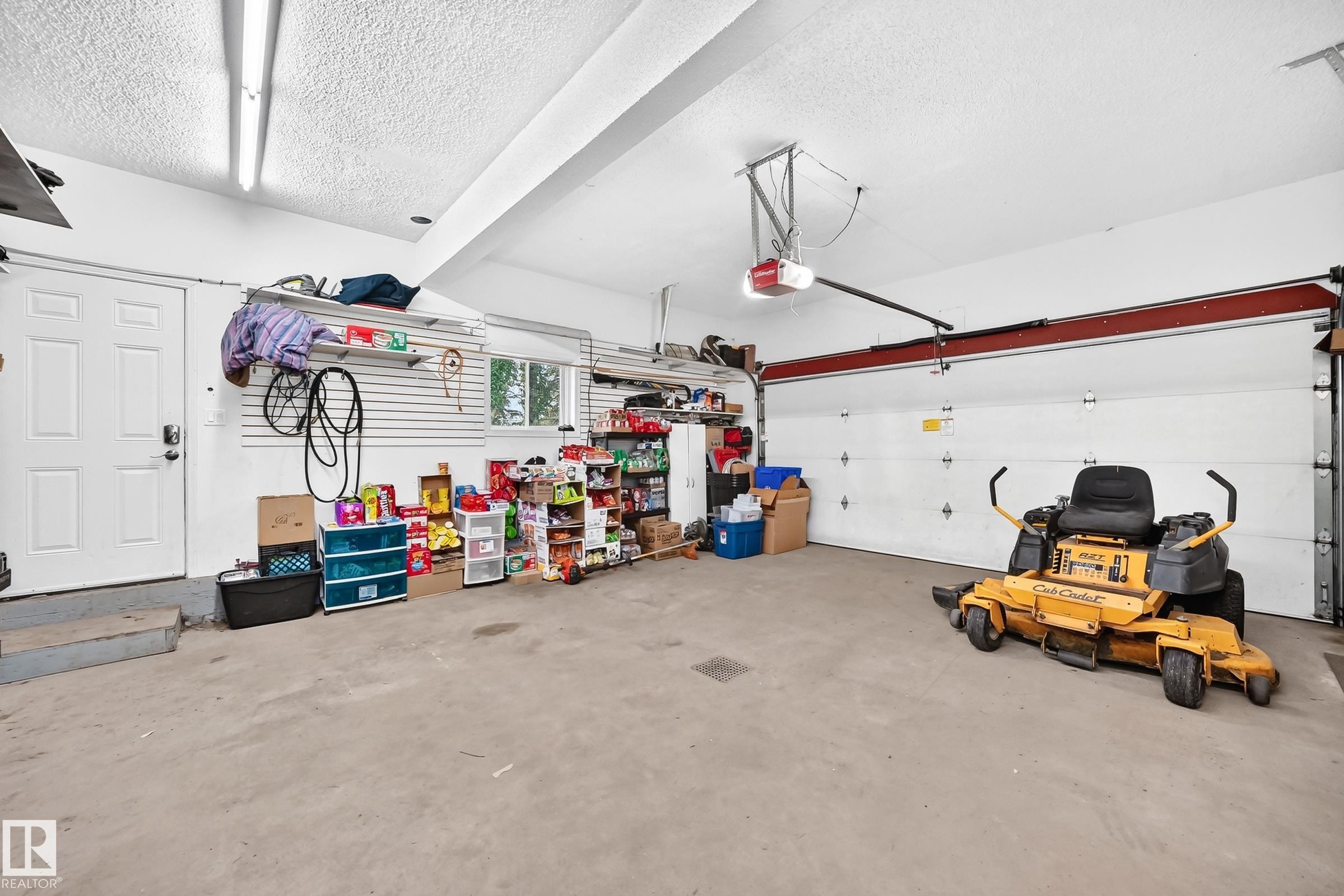 Spacious garage featuring a concrete floor, overhead fluorescent lighting, and an automatic garage door opener - #38 24512 Sturgeon Rd, Rural Sturgeon County, AB