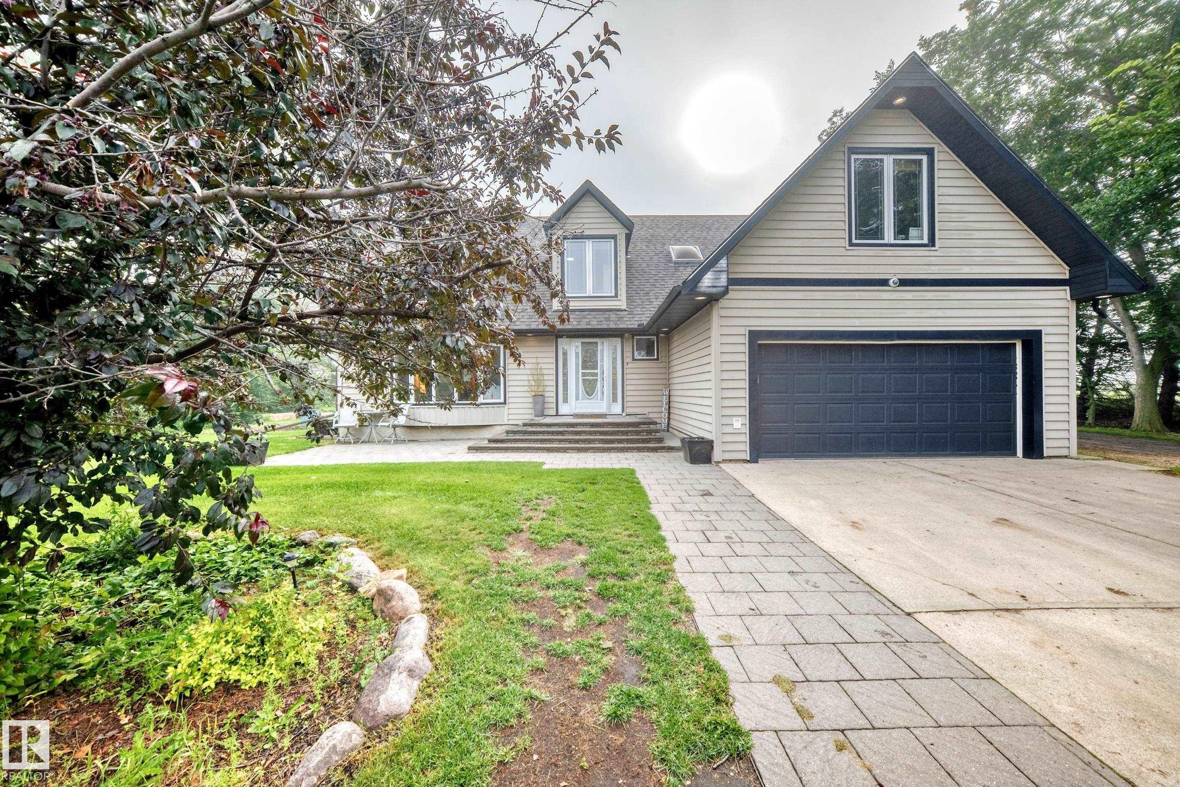 Siding exterior with a dark trim, a two-car garage, and a paver pathway - #38 24512 Sturgeon Rd, Rural Sturgeon County, AB