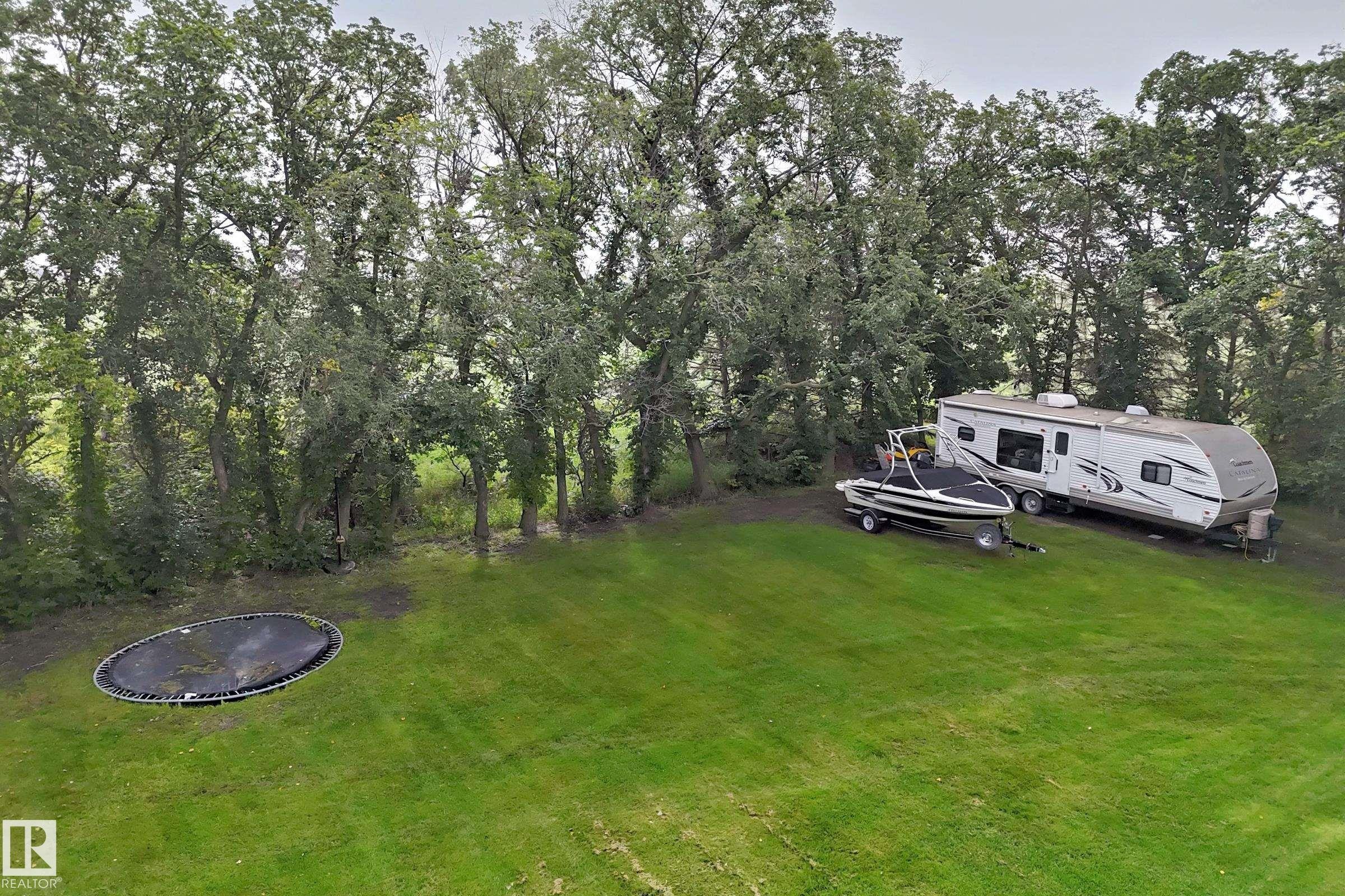 Expansive green lawn surrounded by mature trees - #38 24512 Sturgeon Rd, Rural Sturgeon County, AB