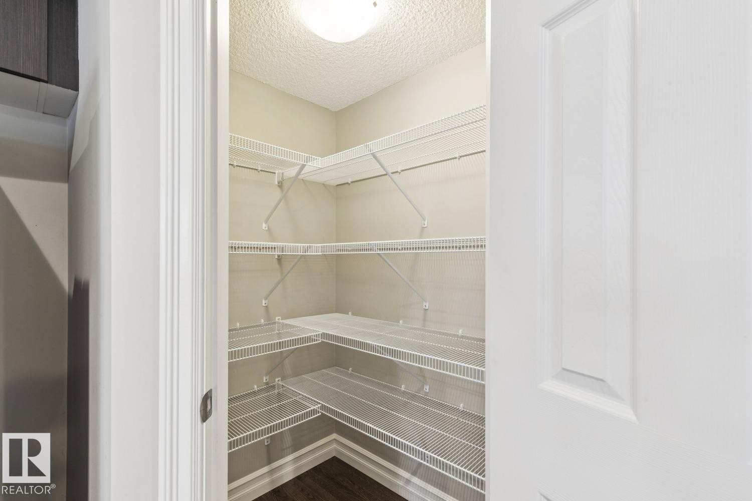 Corner shelving system, interior lighting, and dark wood-finish flooring - 5409 3 Avenue Sw, Edmonton, AB - Indoor With Storage