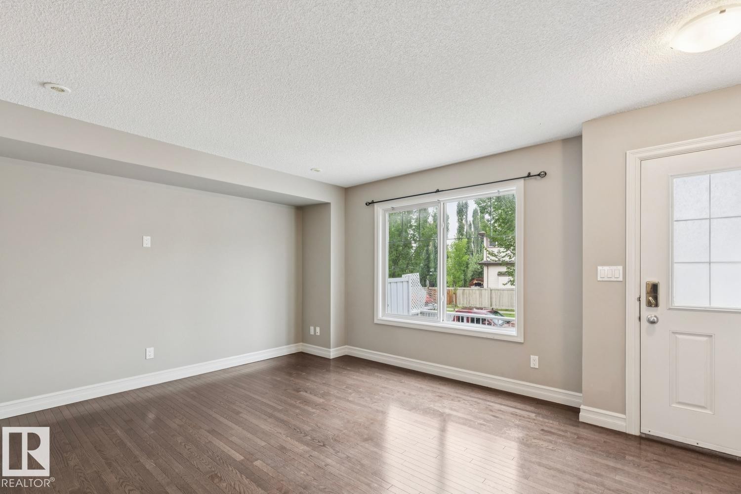 Rich wood-finish flooring, neutral wall tones, and white trim - 5409 3 Avenue Sw, Edmonton, AB - Indoor Photo Showing Other Room