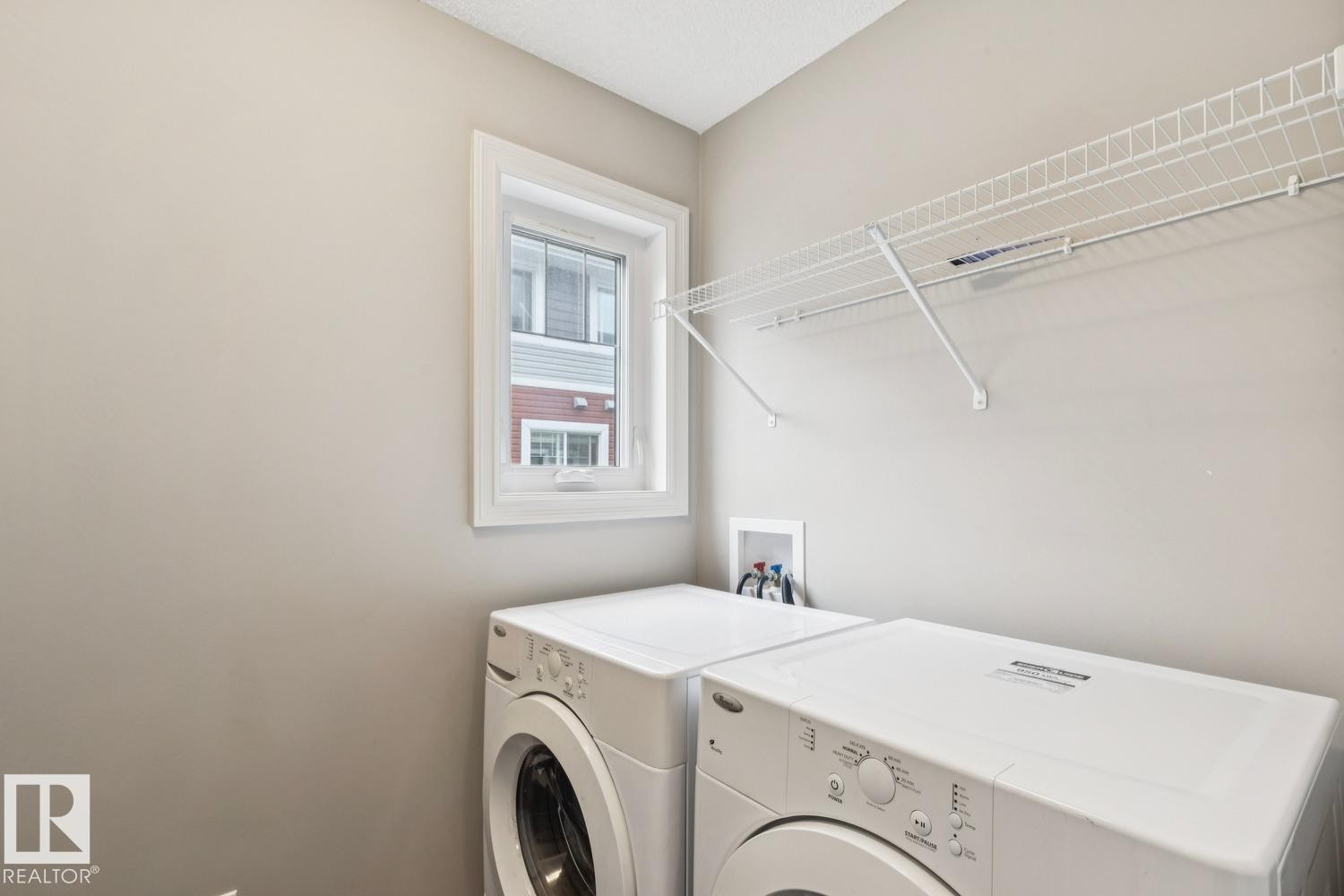 Dedicated laundry space featuring a window, built-in wire shelving, and appliance hookups - 5409 3 Avenue Sw, Edmonton, AB - Indoor Photo Showing Laundry Room