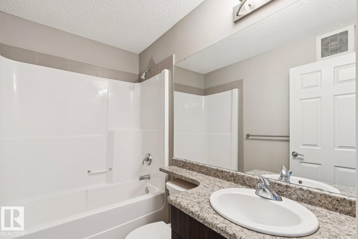 White tub and shower combination with chrome fixtures - 5409 3 Avenue Sw, Edmonton, AB - Indoor Photo Showing Bathroom