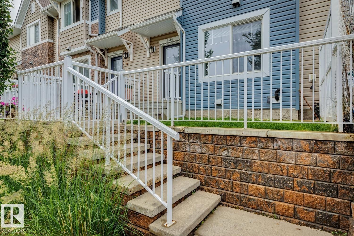 Concrete steps with white railings lead to a private entrance - 5409 3 Avenue Sw, Edmonton, AB - Outdoor