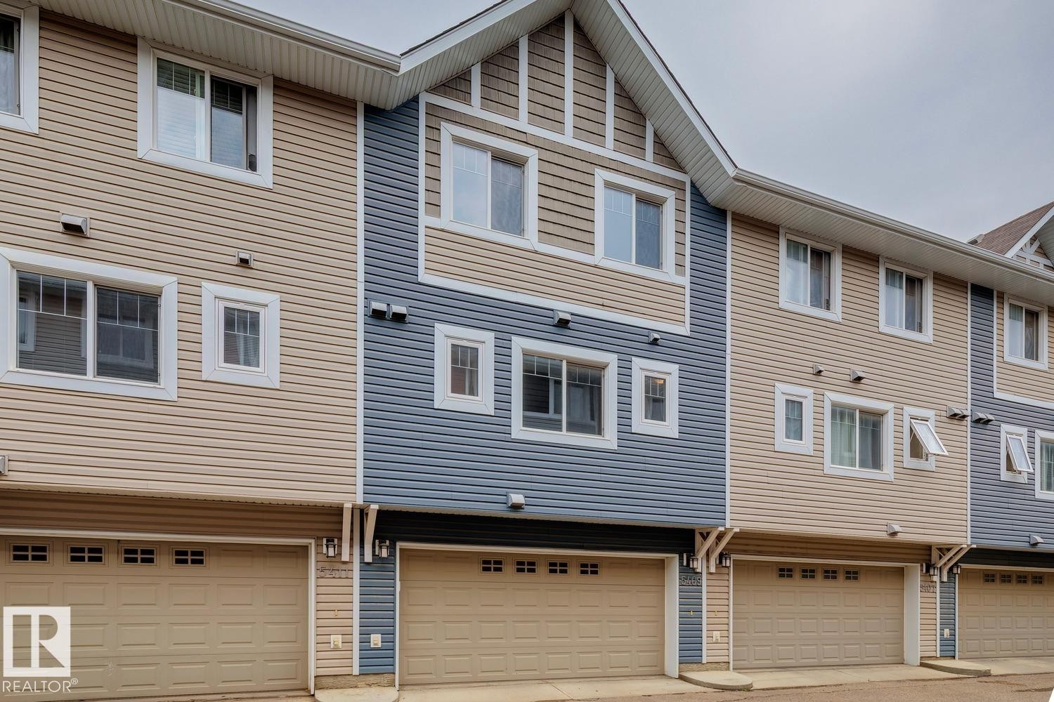 Two-story townhouse exterior with two-tone siding, multiple windows, and an attached garage - 5409 3 Avenue Sw, Edmonton, AB - Outdoor