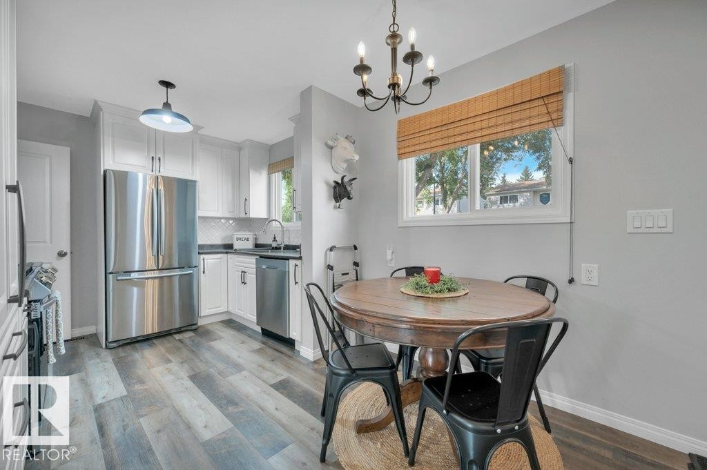 Vinyl plank flooring, white cabinetry, stainless steel appliances, and modern, tiled backsplash - #138 5231 51 St, Bon Accord, AB - Indoor Photo Showing Dining Room