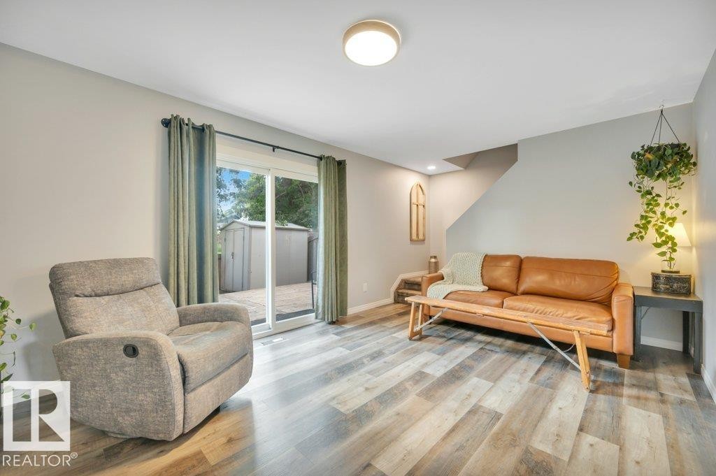 Vinyl plank flooring, light grey wall paint, and a sliding glass door to the exterior - #138 5231 51 St, Bon Accord, AB - Indoor Photo Showing Living Room