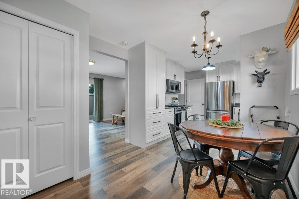 Well-appointed kitchen featuring white cabinetry, stainless steel appliances, and a chandelier light fixture - #138 5231 51 St, Bon Accord, AB - Outdoor