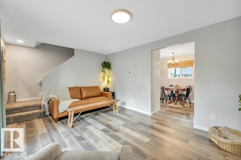 Recessed ceiling light, durable vinyl plank flooring, staircase with carpeted treads, neutral wall paint, and an arched doorway - #138 5231 51 St, Bon Accord, AB - Indoor Photo Showing Living Room