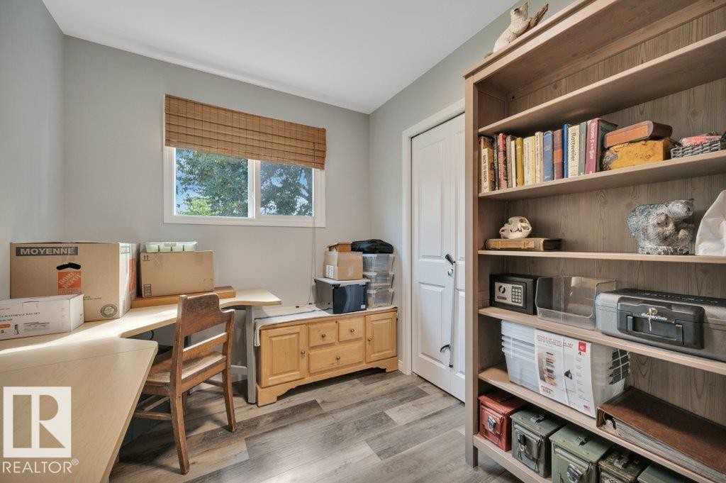 Vinyl plank flooring, built-in shelving unit, natural light from a window, and a built-in wooden cabinet - #138 5231 51 St, Bon Accord, AB - Indoor Photo Showing Office