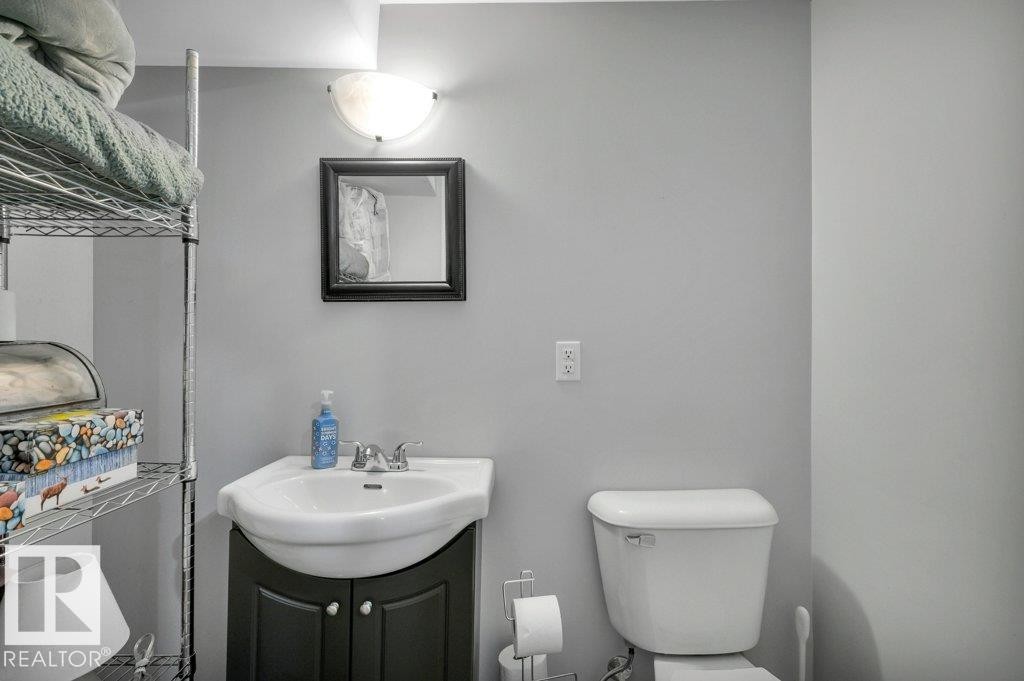 Wall-mounted vanity light, framed mirror, pedestal sink with cabinet storage, and toilet - #138 5231 51 St, Bon Accord, AB - Indoor Photo Showing Bathroom