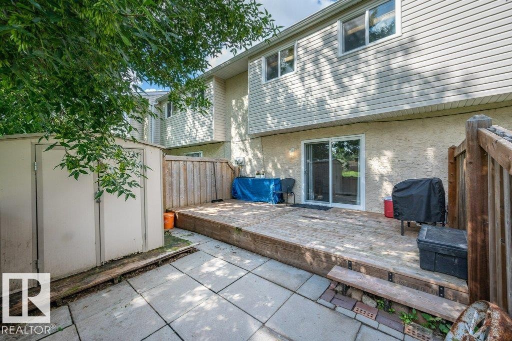 Rear exterior with a wood deck, sliding glass door, and an accompanying patio area - #138 5231 51 St, Bon Accord, AB - Outdoor With Exterior