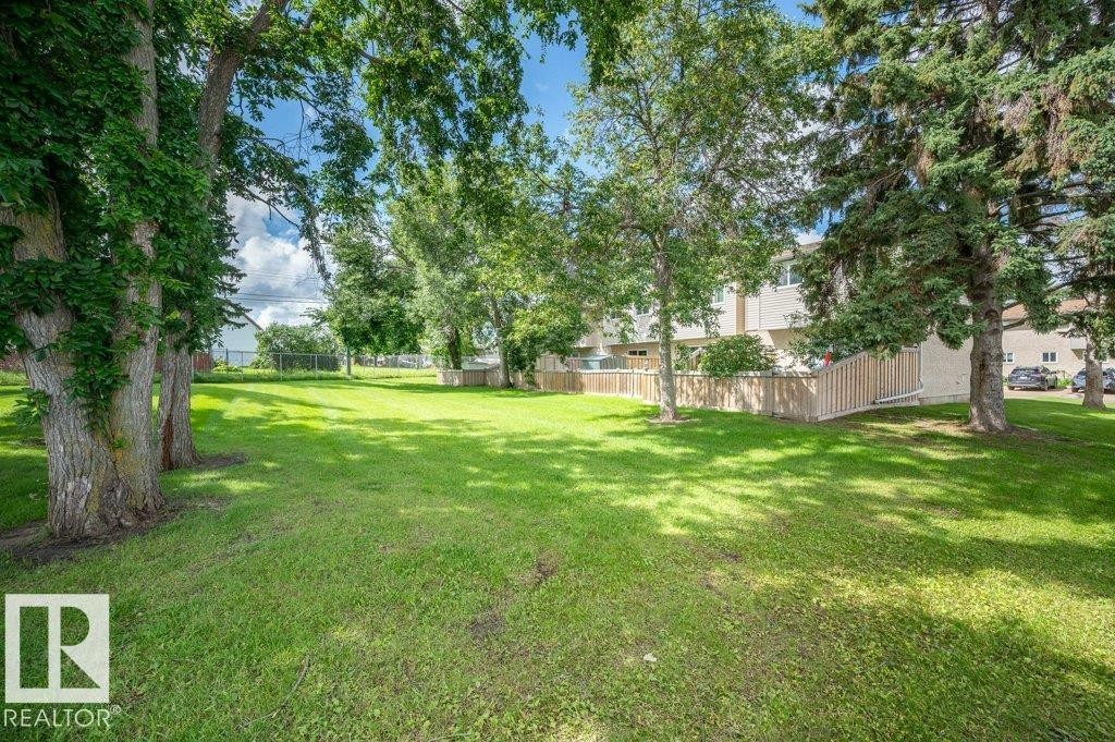 Expansive green space featuring mature trees and a partial wood fence - #138 5231 51 St, Bon Accord, AB - Outdoor